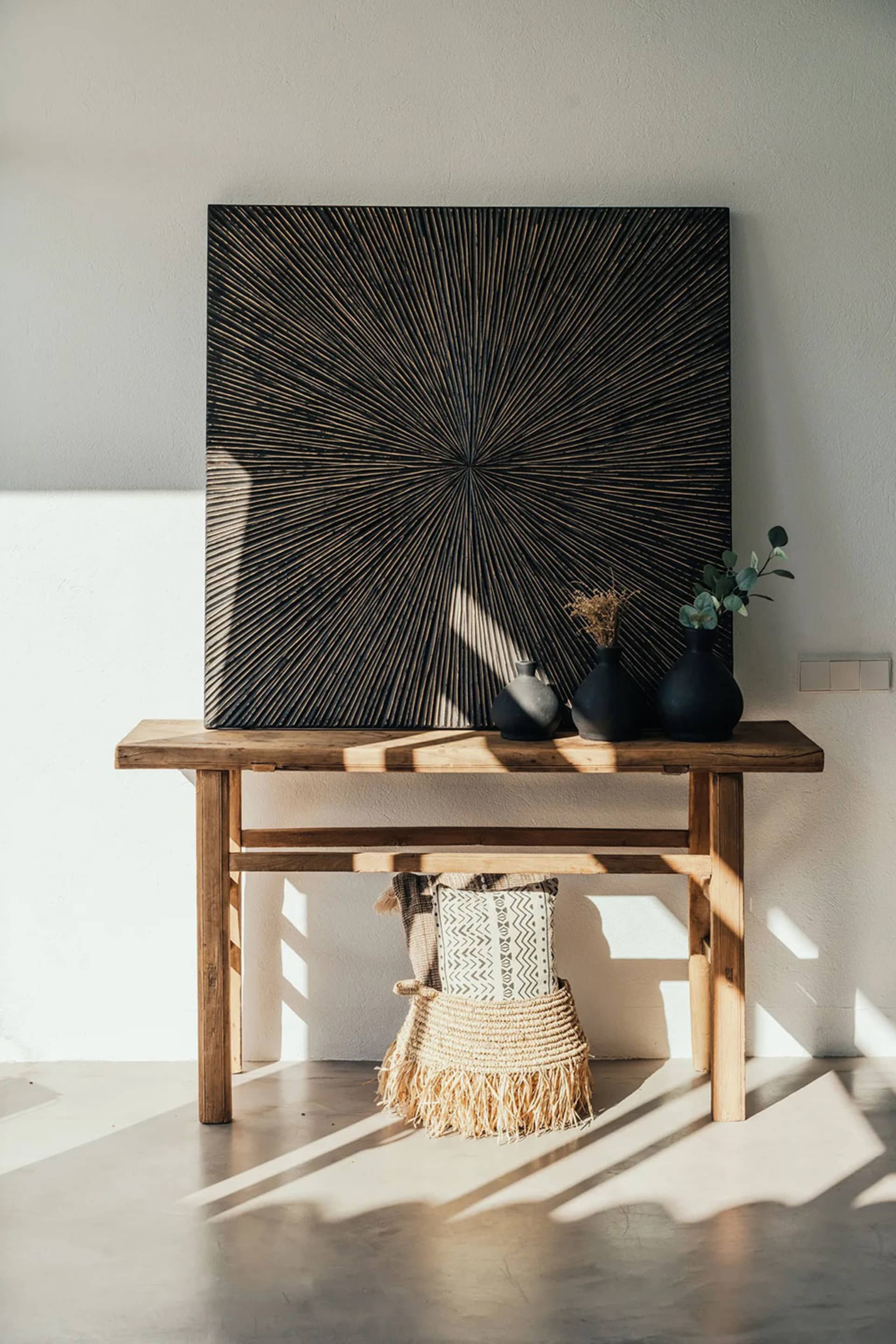 A modern console table crafted from wood with a minimalist design, featuring black vases and decorative items on top.