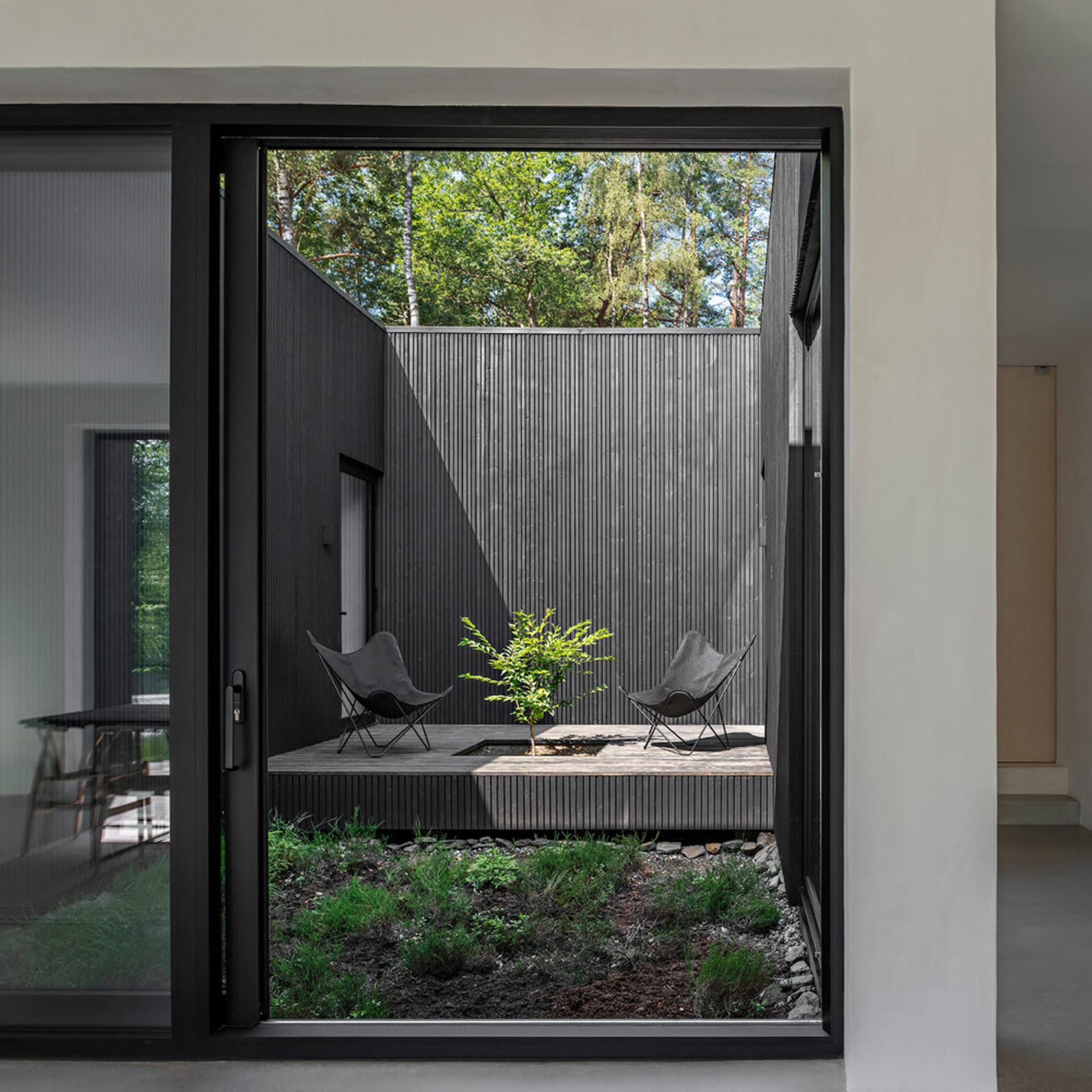 A modern outdoor space featuring wooden elements and metal chairs.