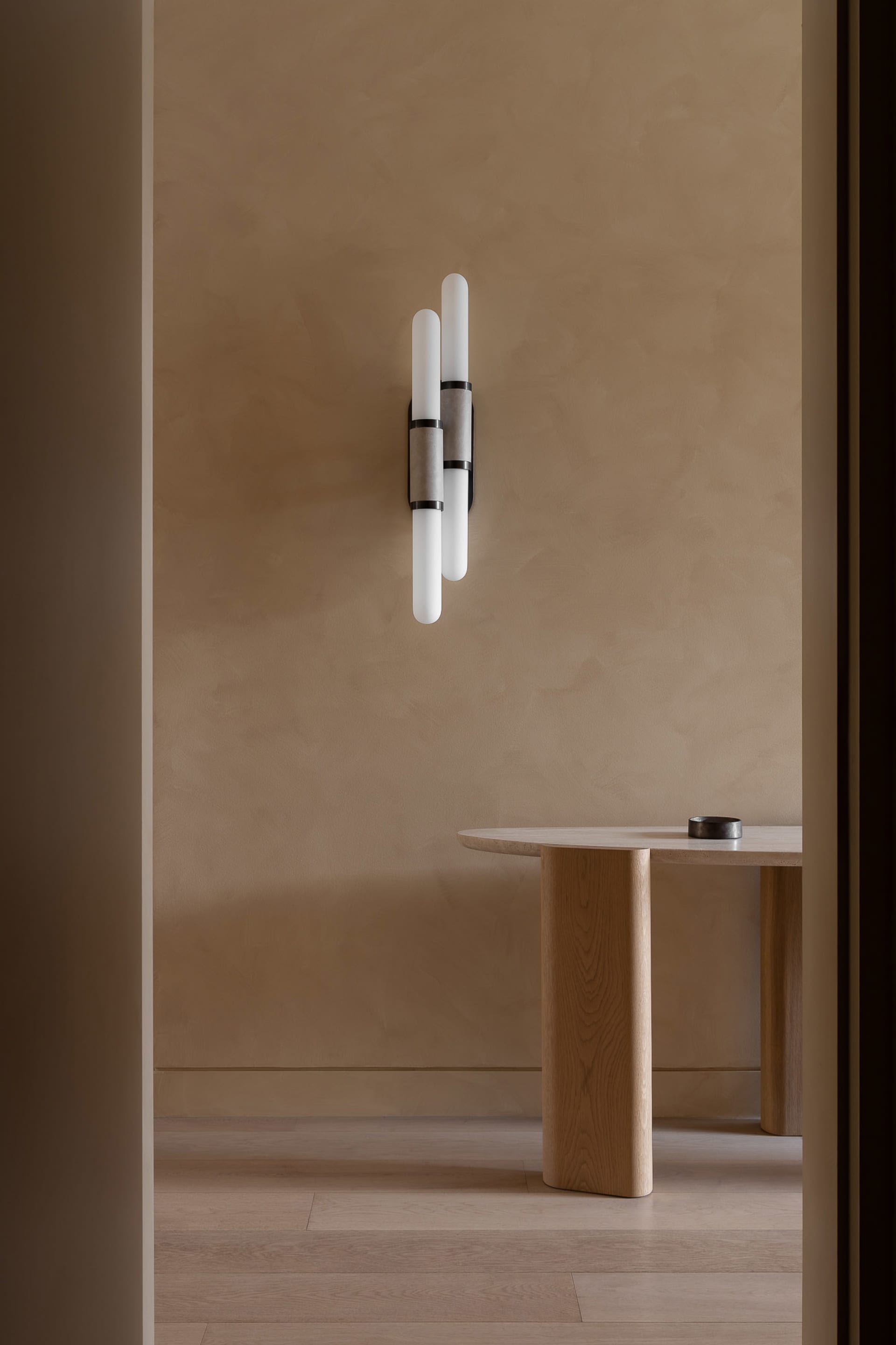 A minimalist interior showcasing wooden elements, concrete accents, and modern lighting against a beige textured wall.