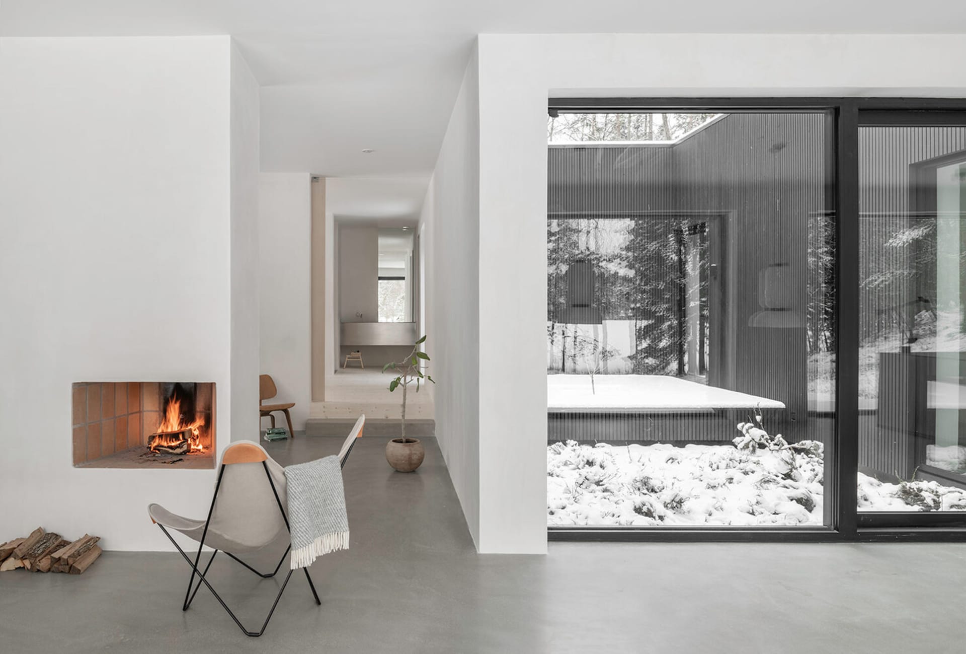 Minimalist living room with concrete floor, glass windows, and fireplace.