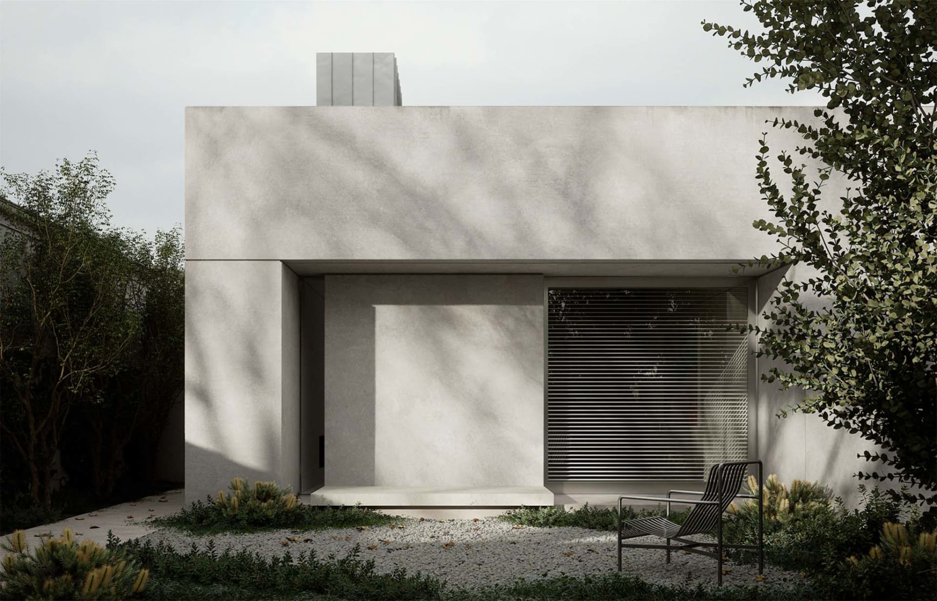 A minimalist concrete house with a modern exterior and metal chair in front of it.