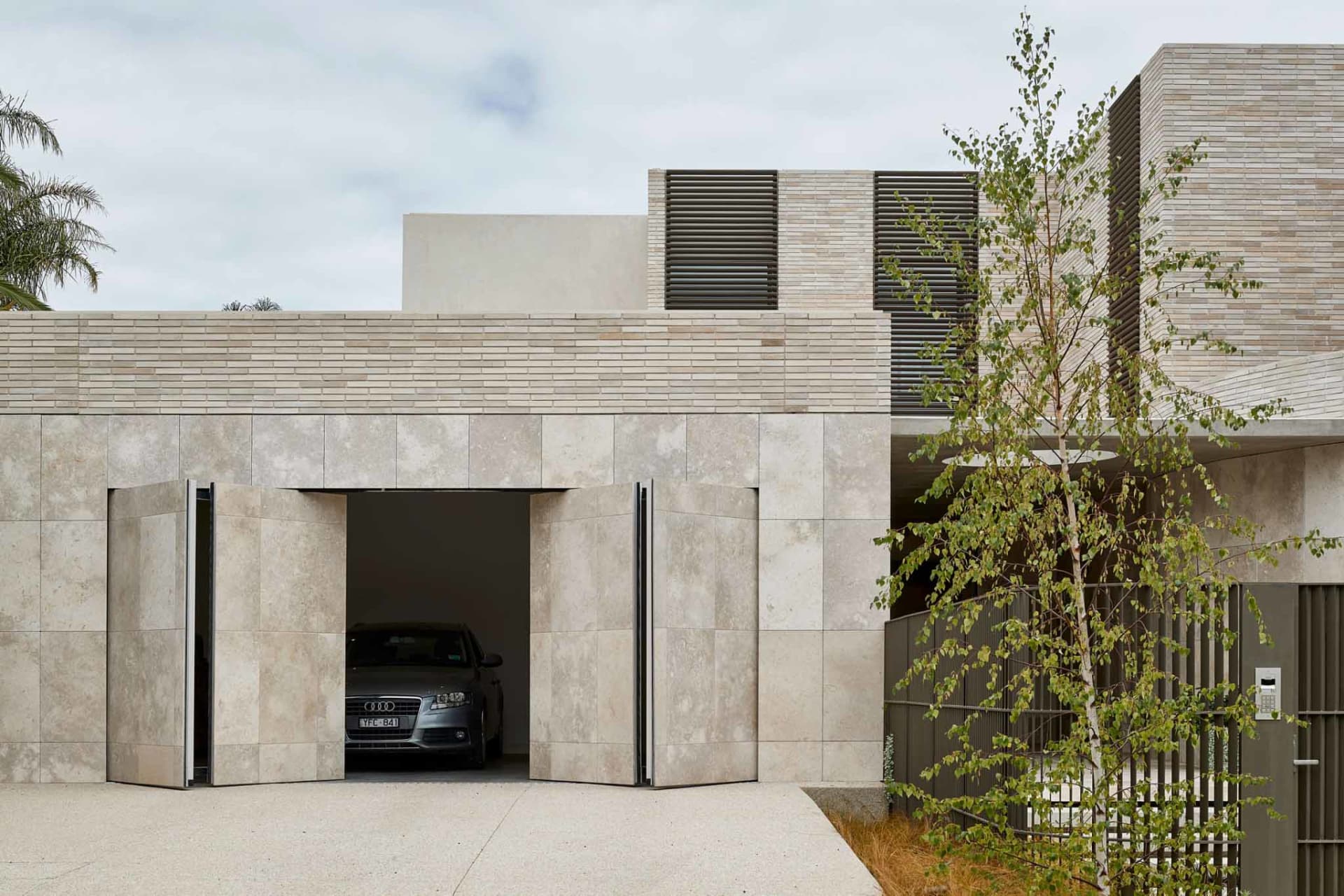 Modern architectural house with a concrete entry gate and a car parked inside.