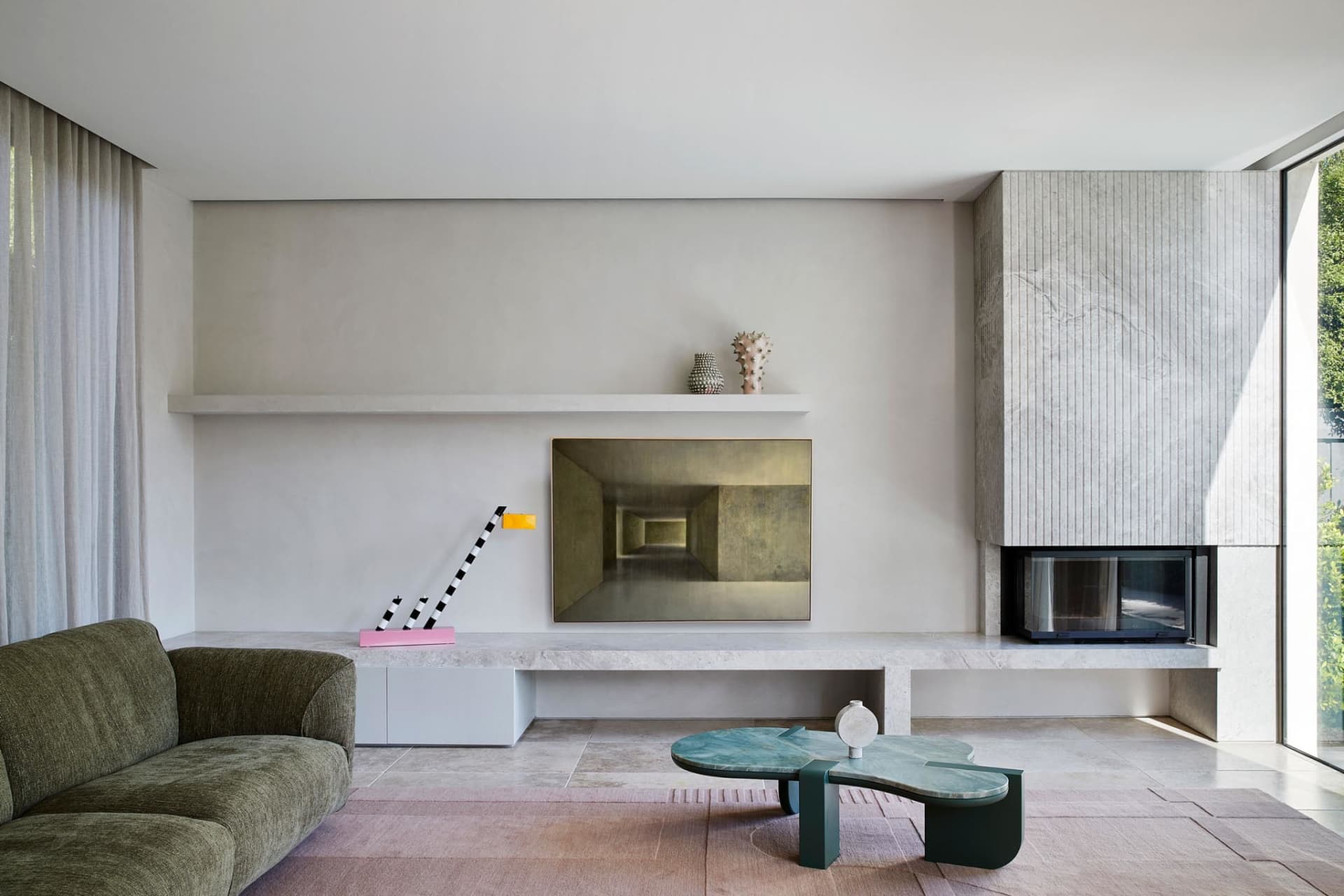 A minimalist living room with a concrete fireplace, large windows, and a simple sofa.