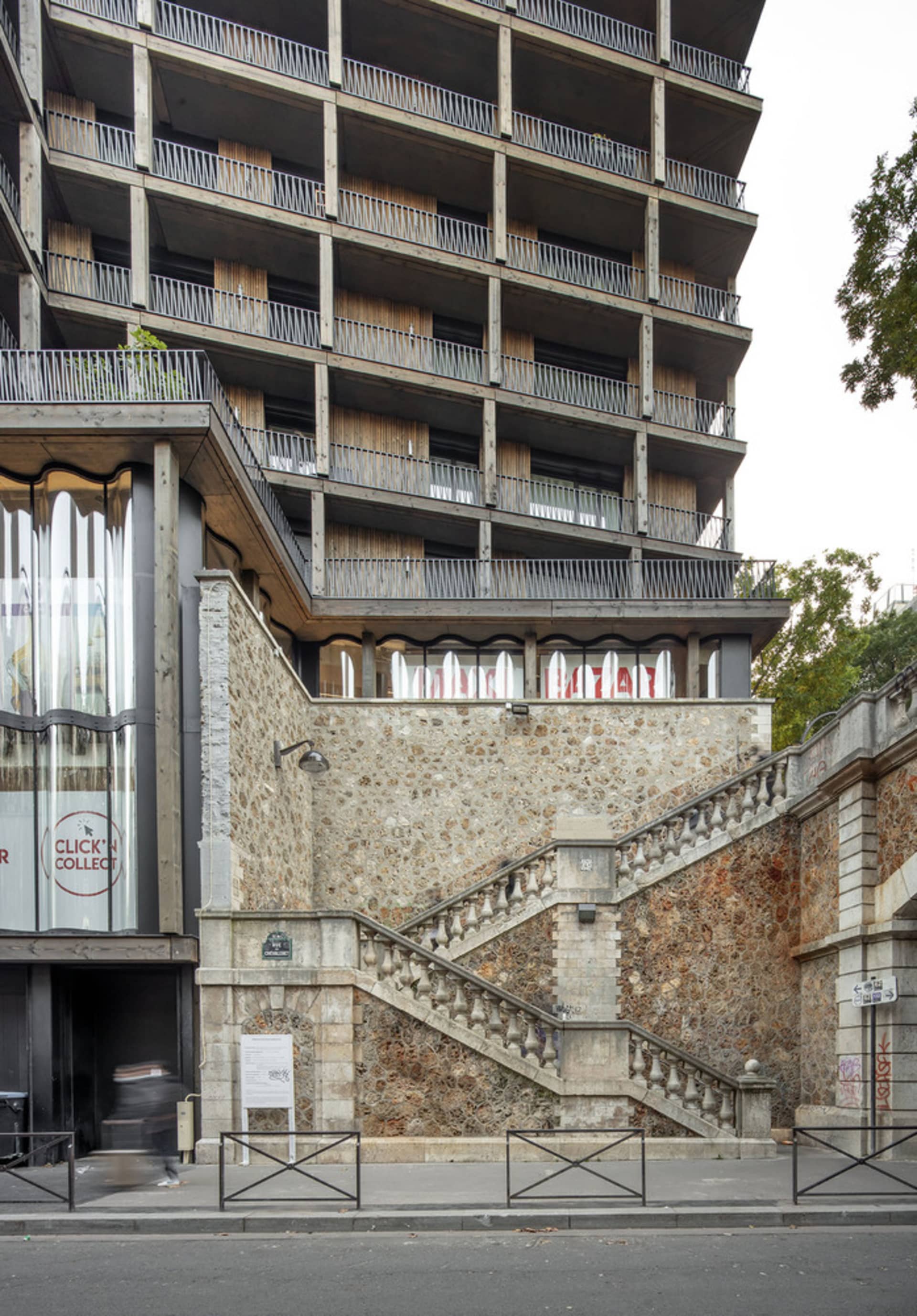 一座由混凝土建造的現代住宅建築,搭配玻璃窗與金屬欄杆。