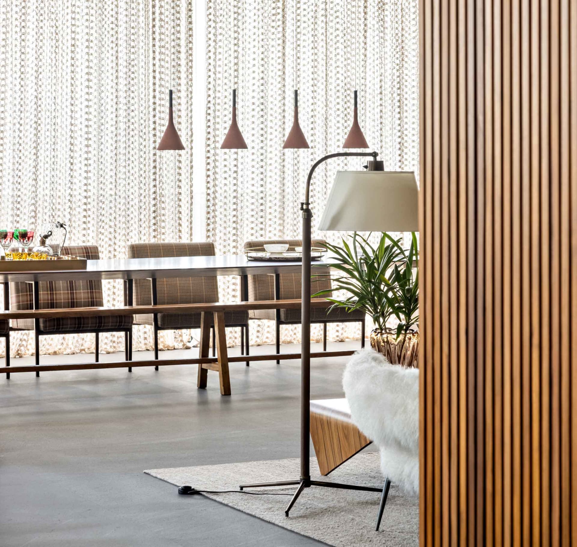 A modern dining room with wooden furniture and pendant lights.