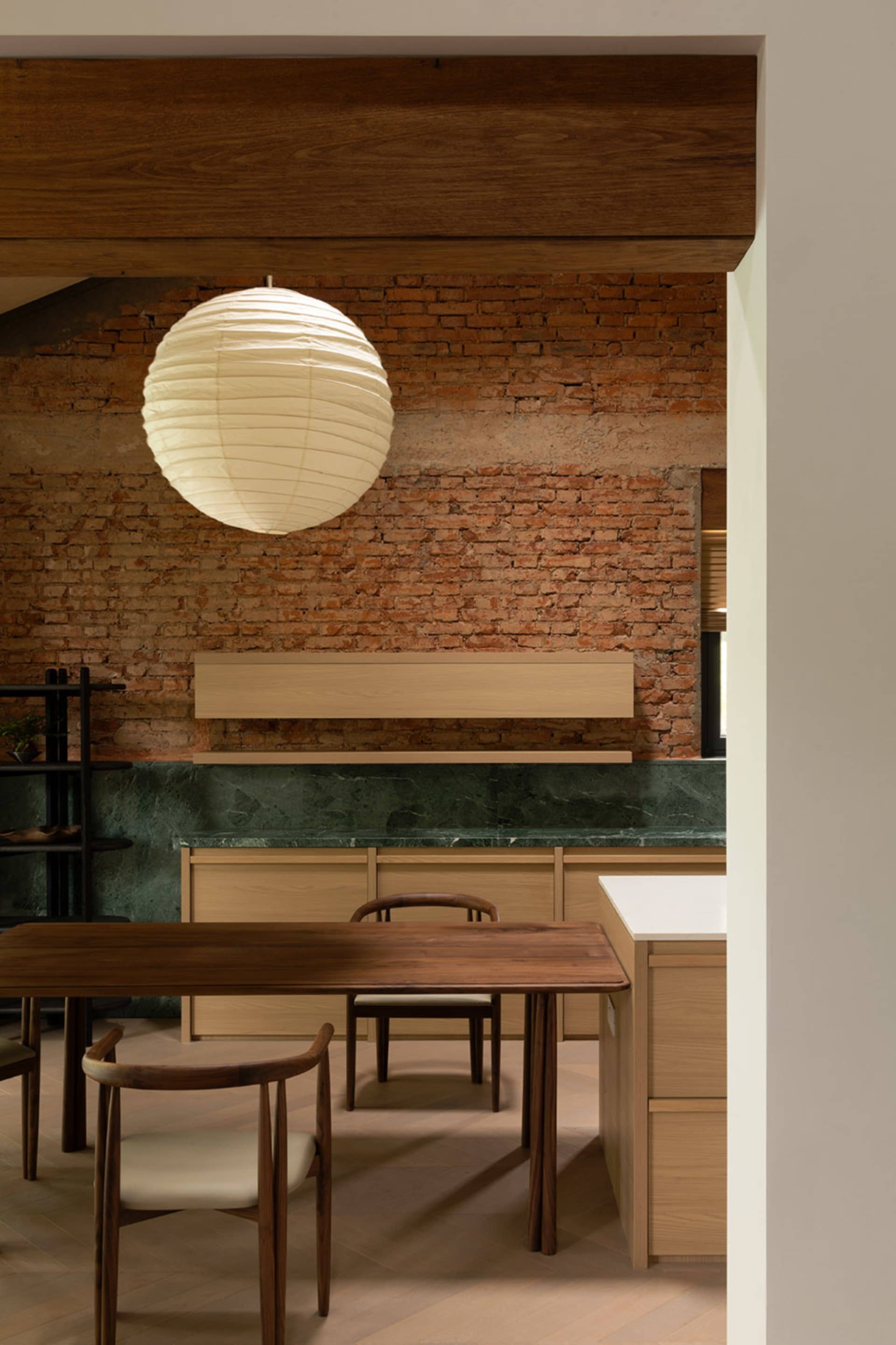 Modern kitchen featuring wooden furniture, brick wall, and marble countertop