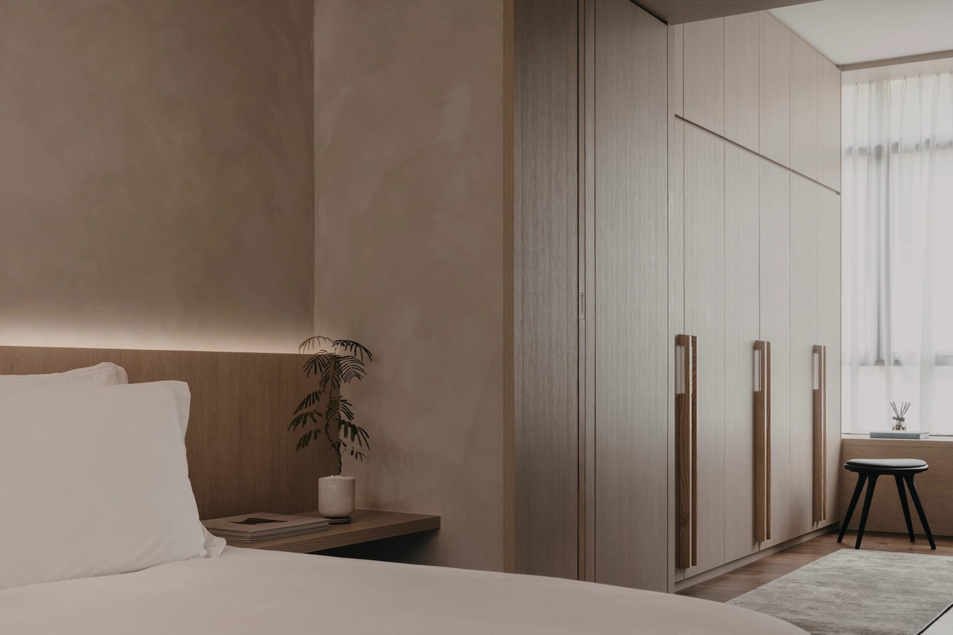 A modern minimalist bedroom with a wooden bed frame, a wooden headboard, and wooden furniture.