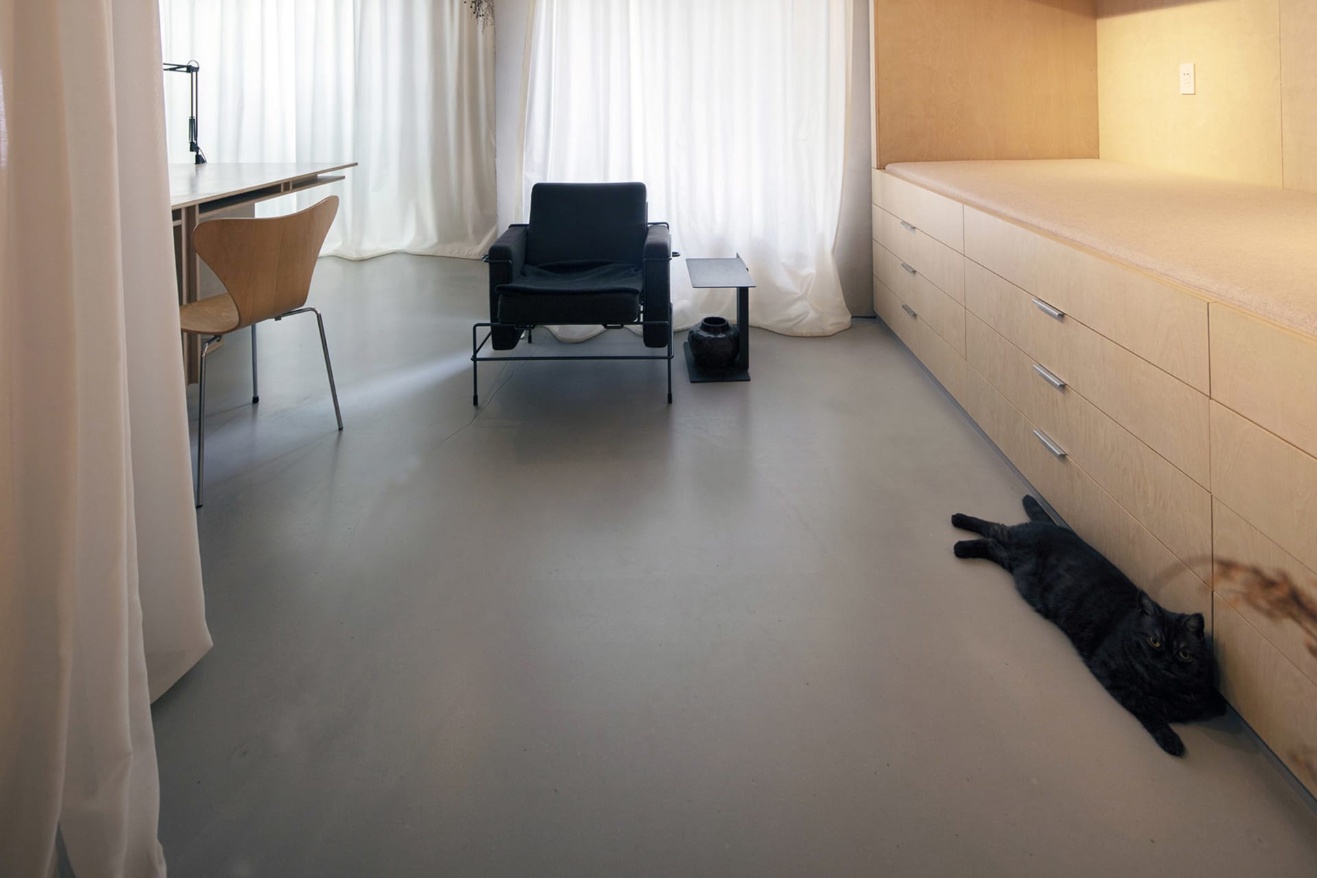 Modern, minimalist living space with concrete flooring and furniture.