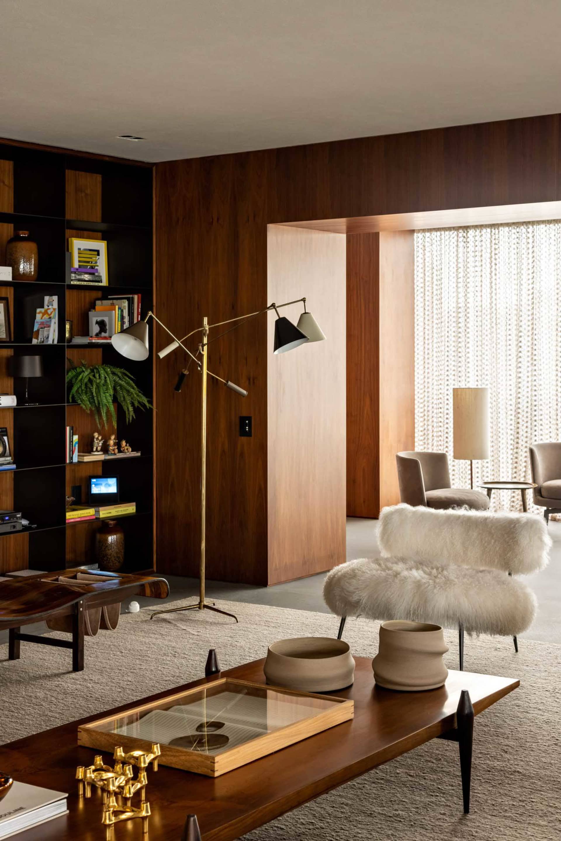 Modern living room featuring a wooden floor, fabric chairs, ceramic vases, and brass floor lamp.
