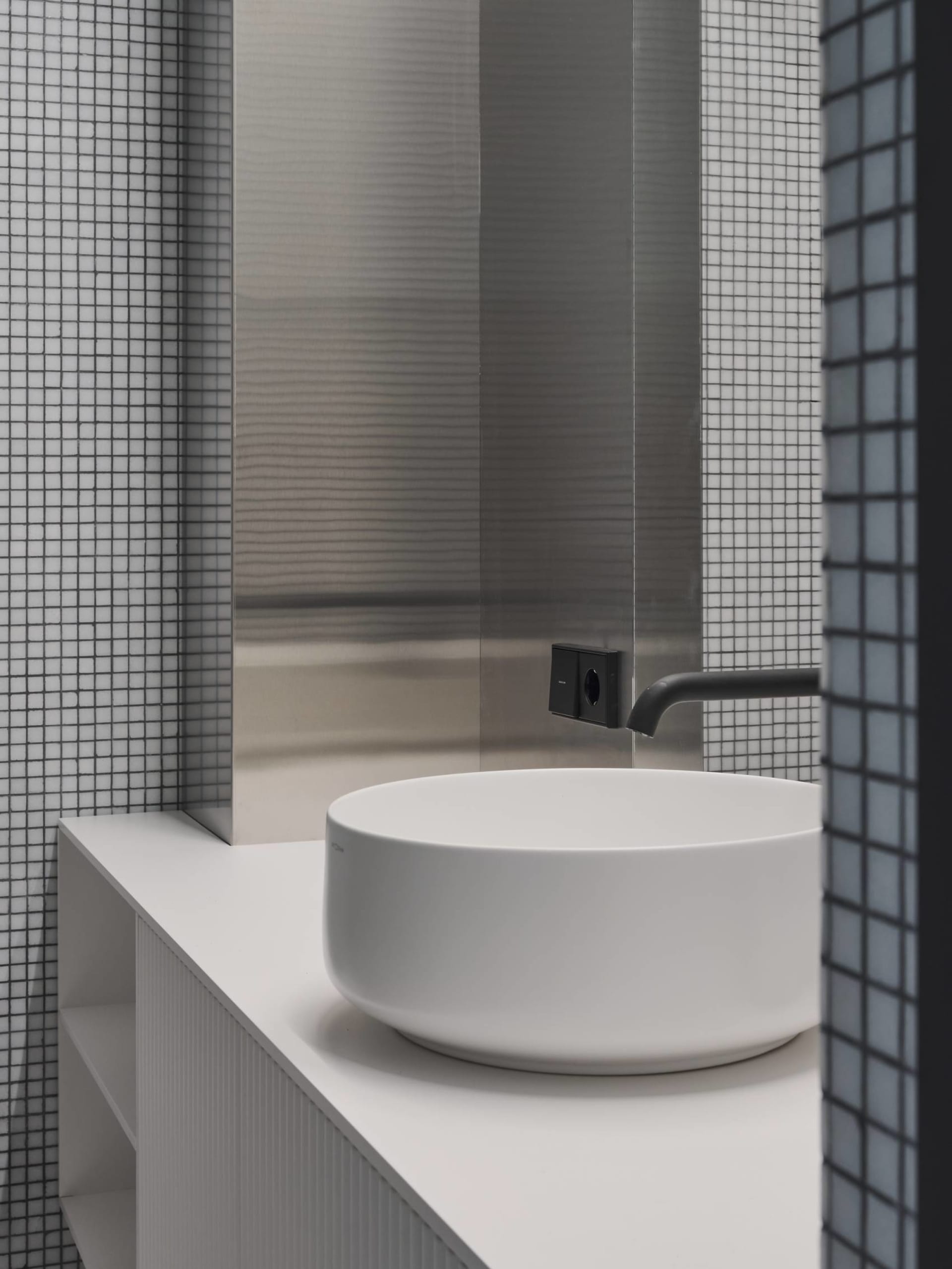 A modern bathroom with a round white ceramic sink and a minimalist design.