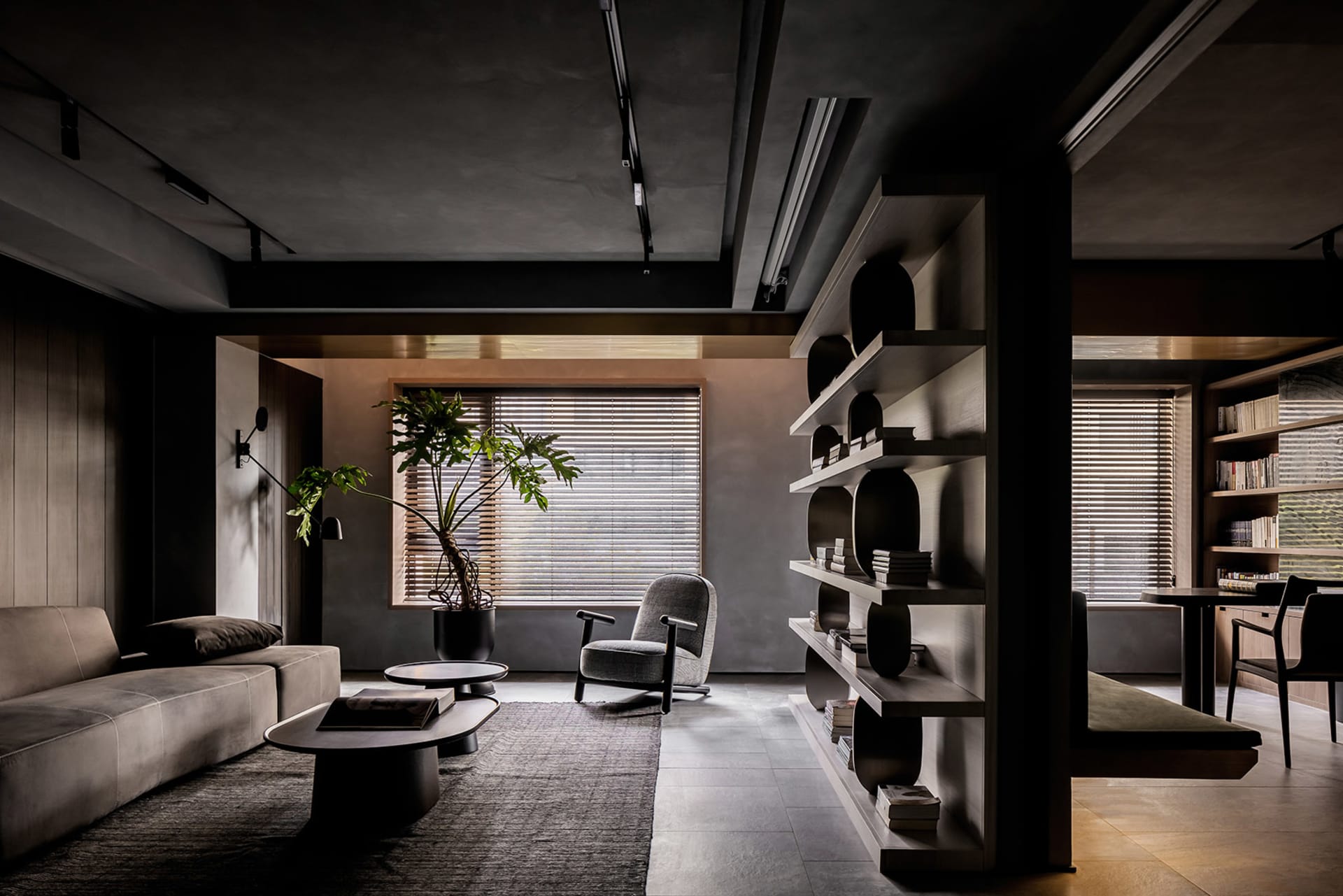 A modern interior living room with concrete, wood, and leather materials, featuring a cozy sofa, armchair, bookshelves, and p