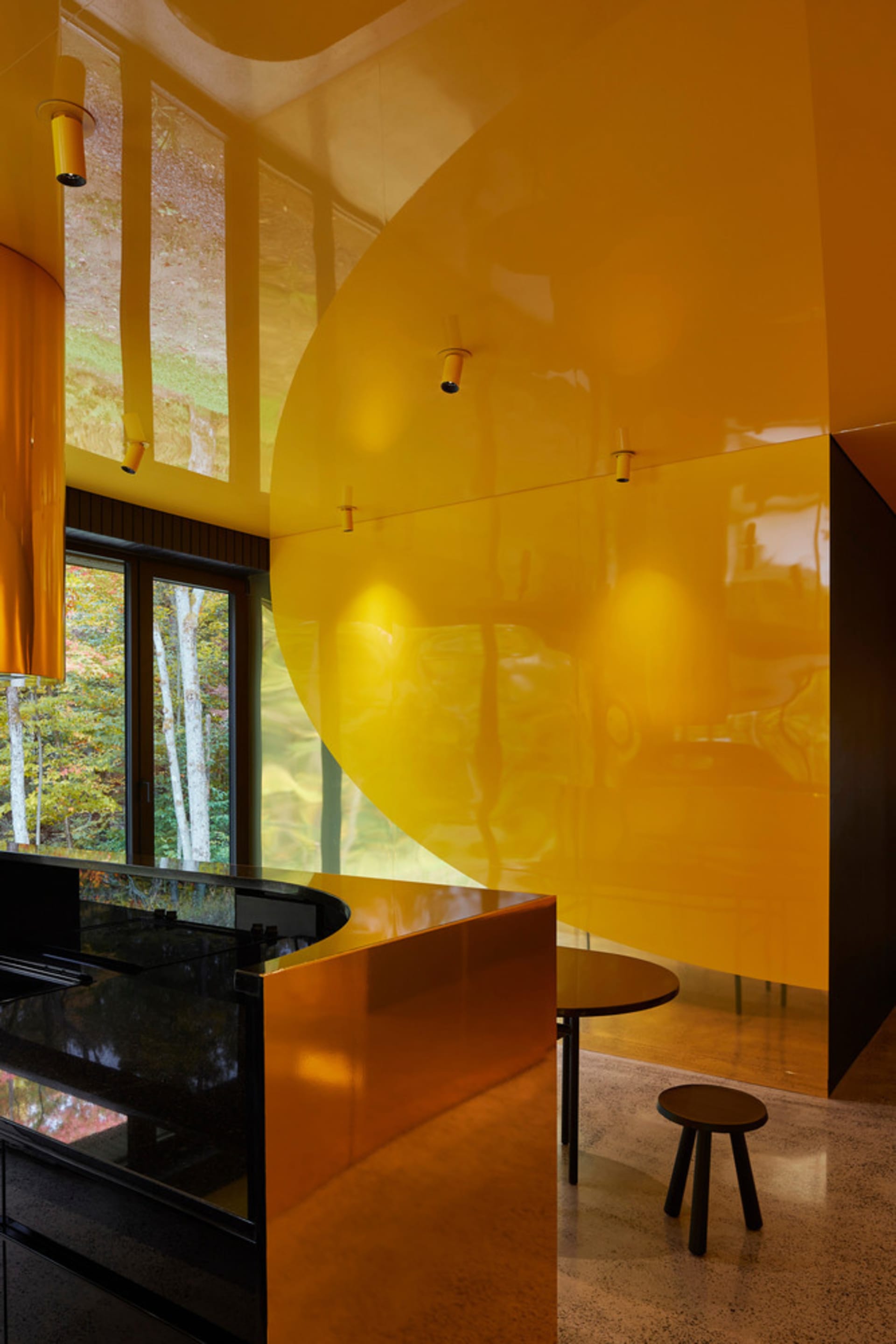 A modern kitchen featuring yellow glass surfaces and metal accents.