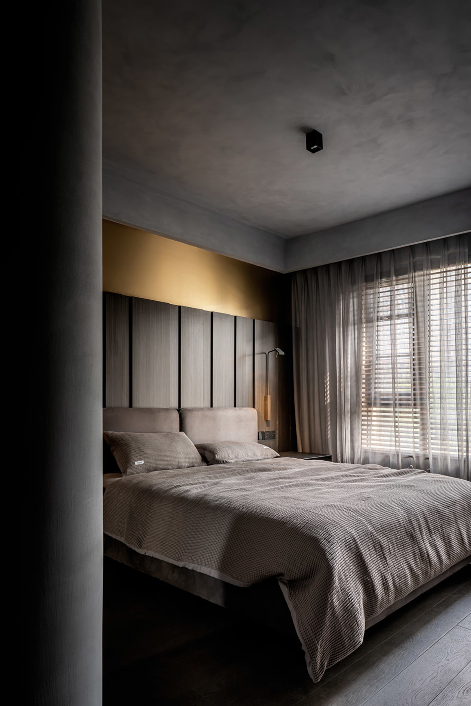 A modern minimalist bedroom featuring dark fabrics and a cozy ambiance.