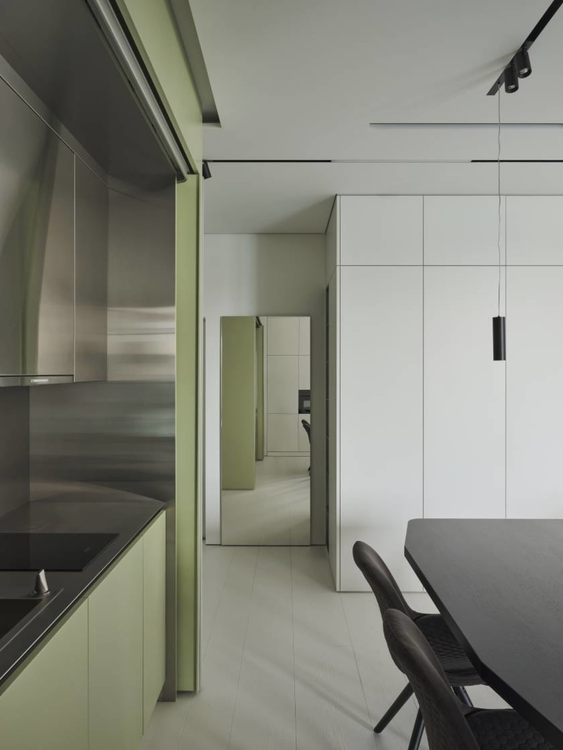 Modern minimalist kitchen with stainless steel appliances, green cabinetry, and white countertops.