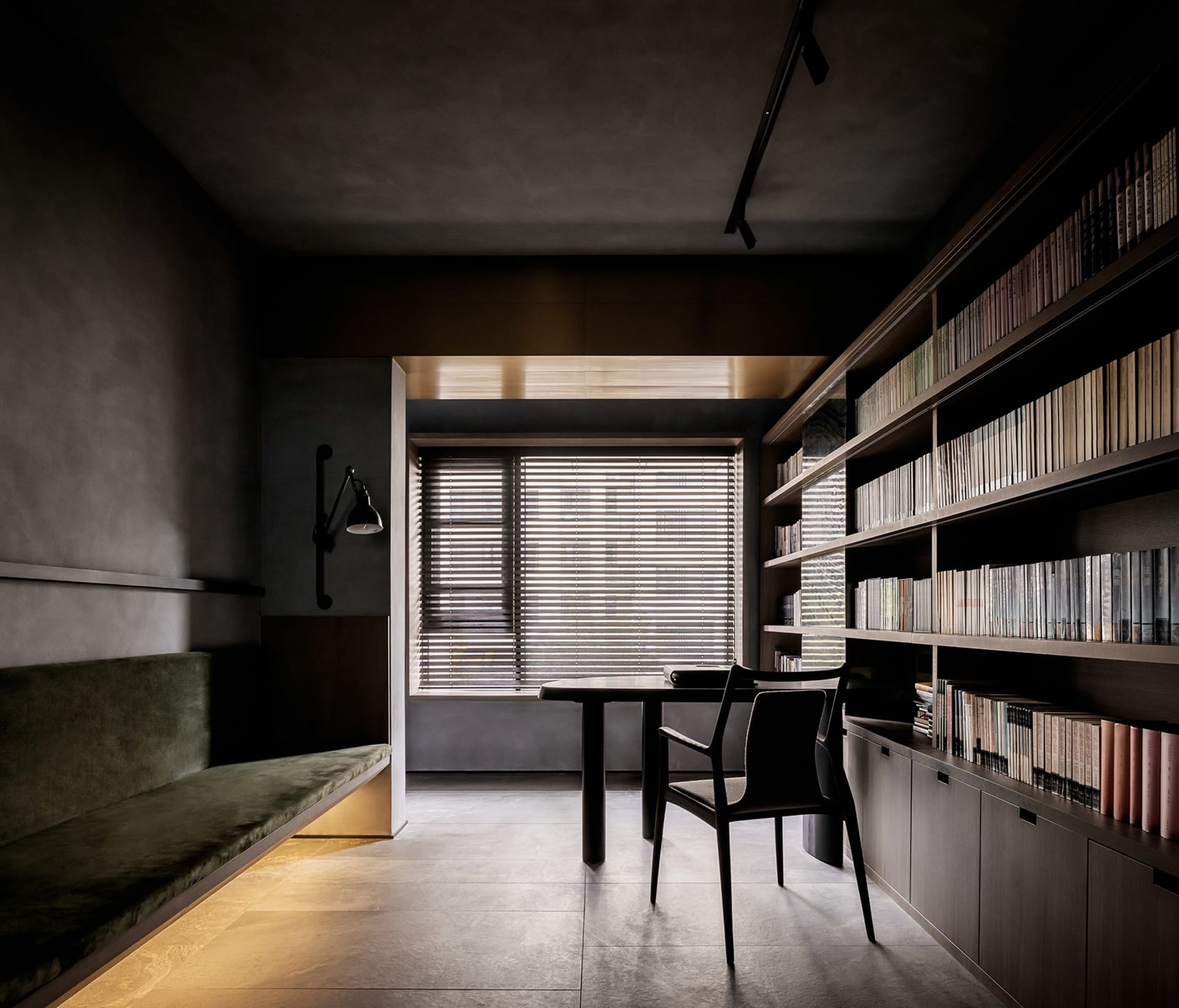A modern minimalist library with dark wood furniture and shelving filled with books.