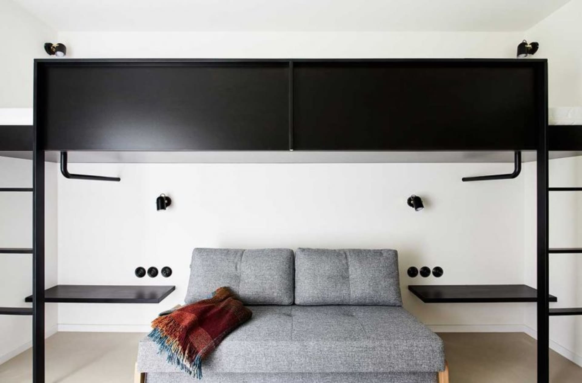 Clean, modern living room with black metal furniture, white walls, and a cozy sofa.