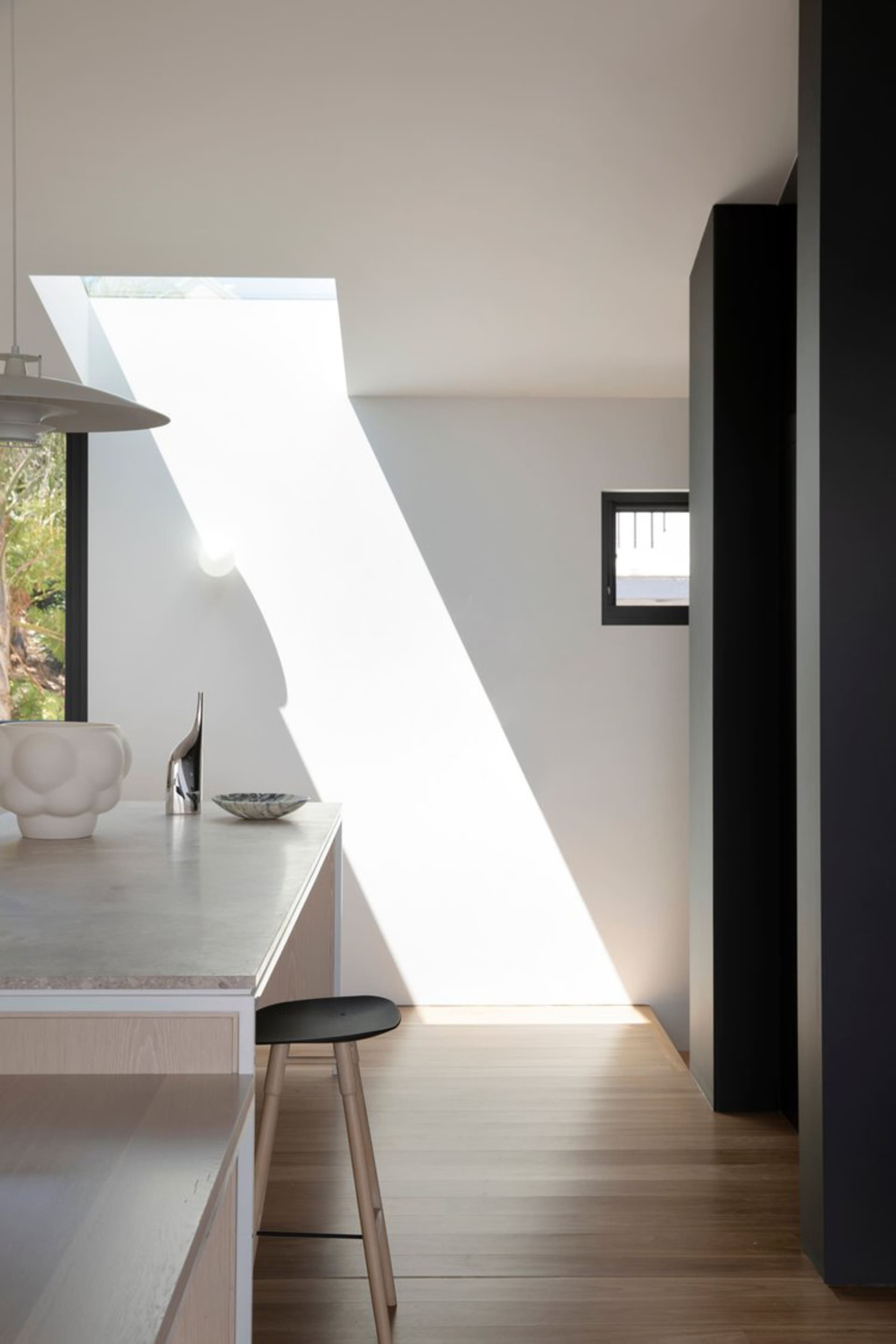 A modern kitchen featuring a concrete countertop, with a skylight casting natural light.