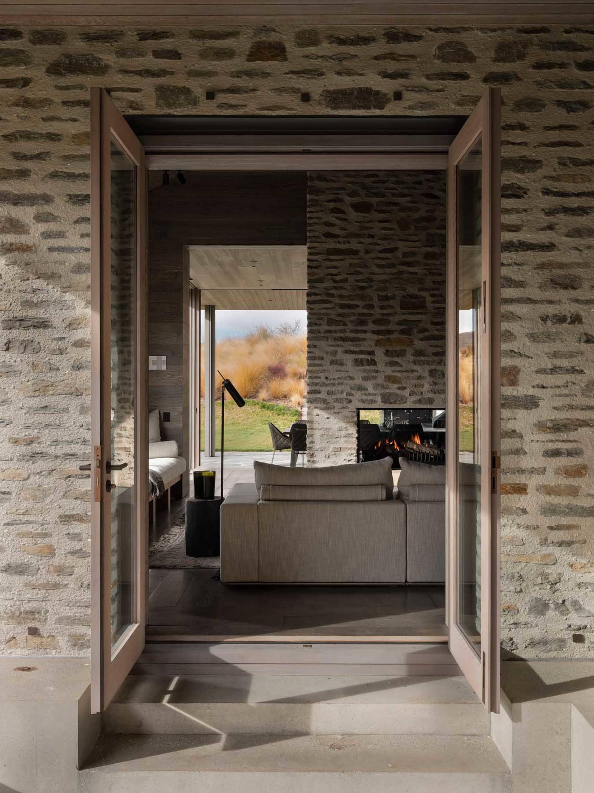 A contemporary living room with stone walls and concrete floors.