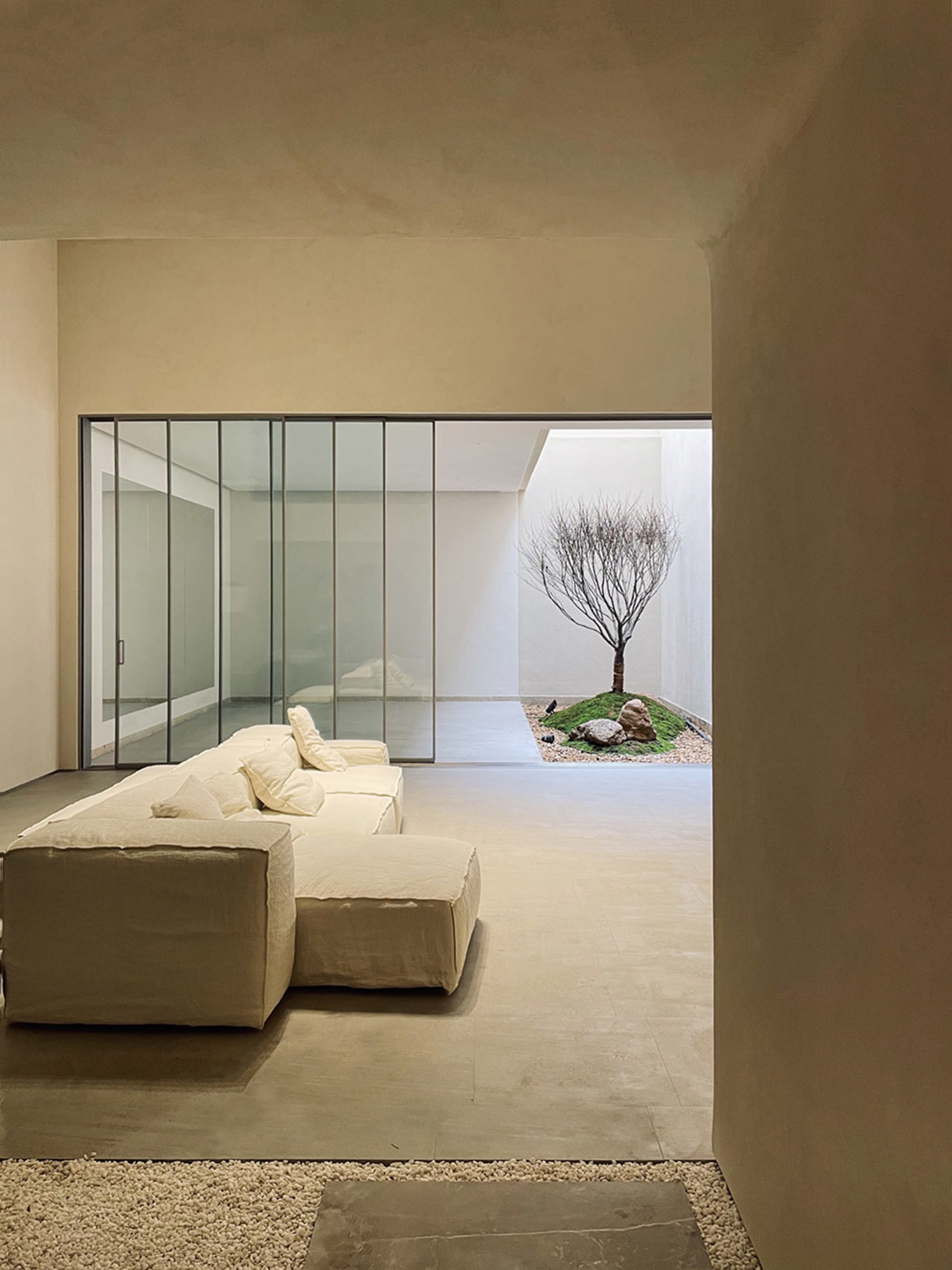 Modern interior with concrete walls, floor, and minimalist furniture, featuring a living room space with a large window and a