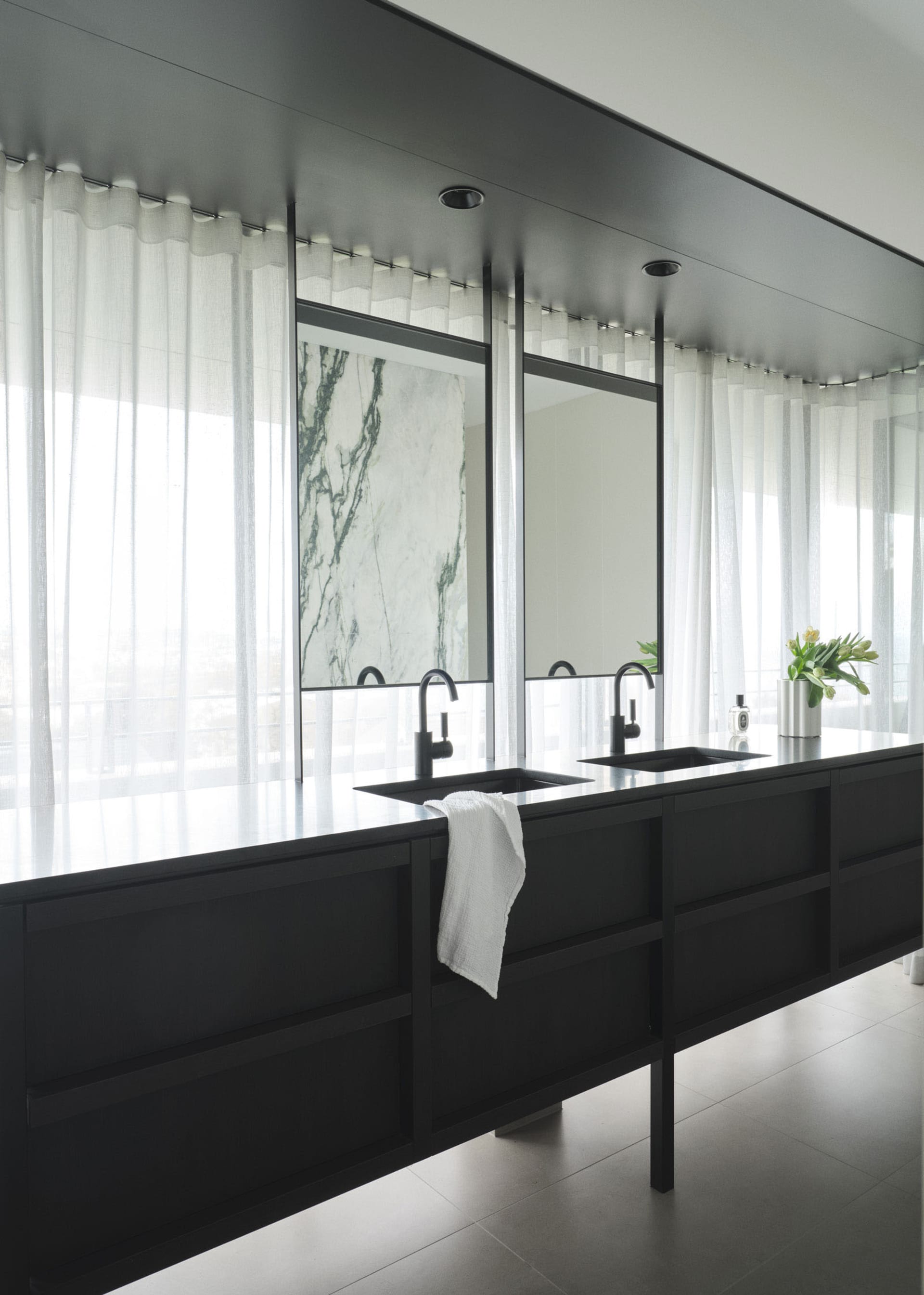 Modern, minimalist bathroom featuring a marble countertop with black fixtures.