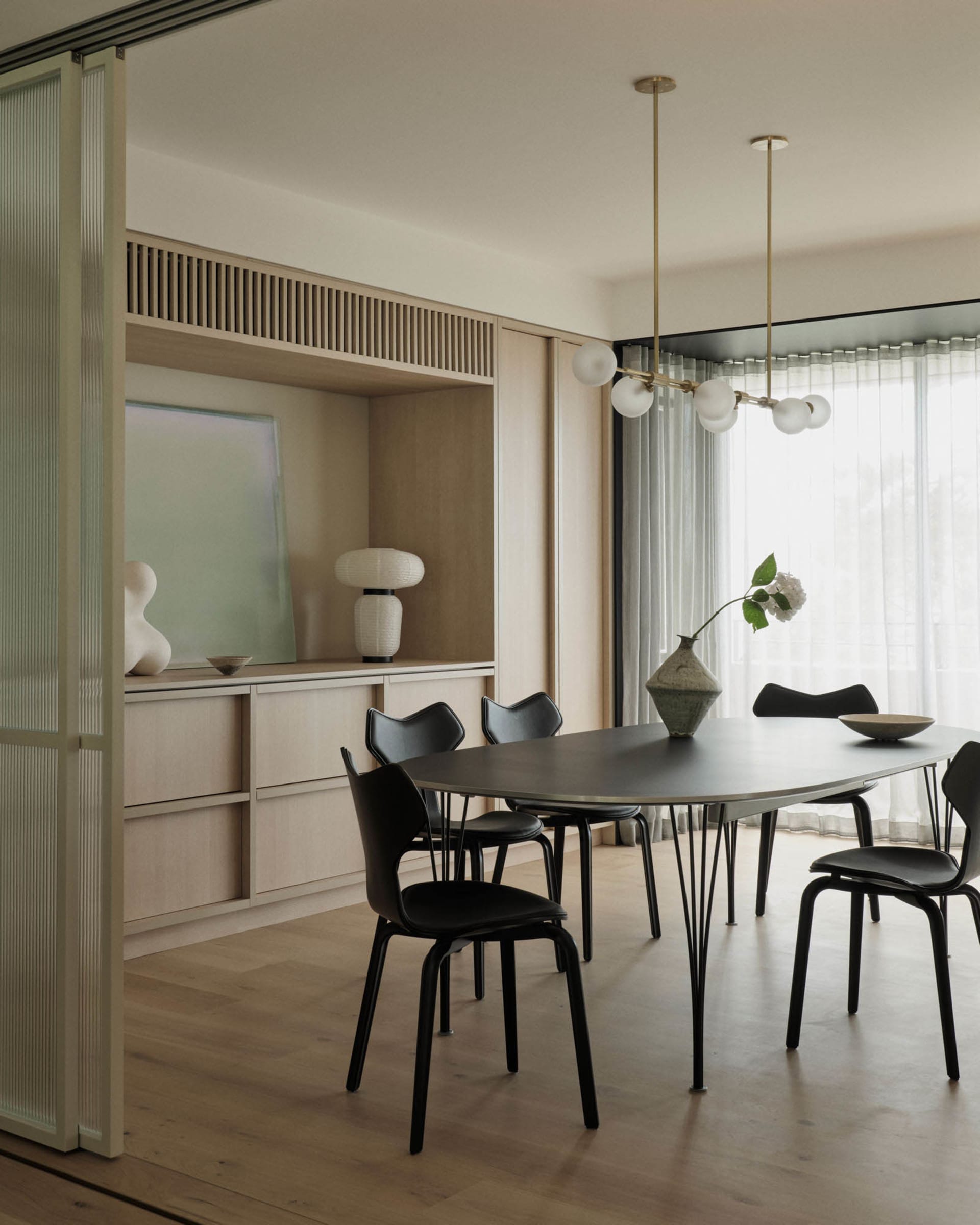 A modern residential dining room featuring a sleek table, black chairs, and a minimalist decor.