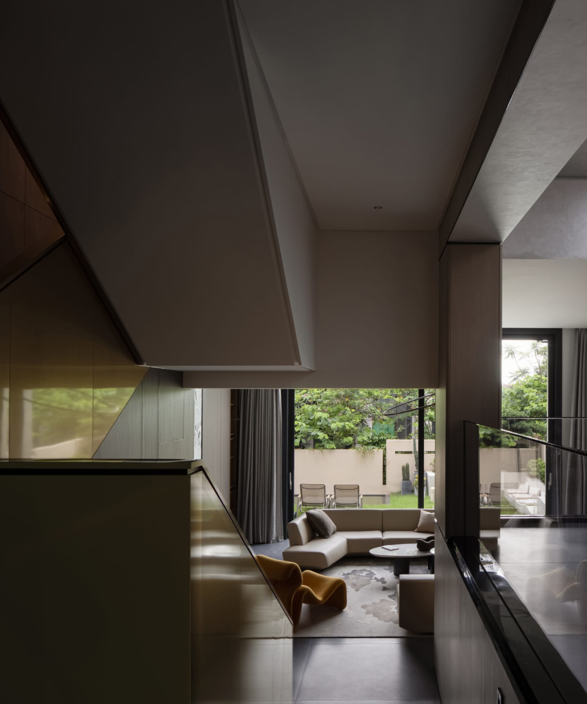 A modern residential space with glass and steel materials, featuring a comfortable seating area and an open concept design.