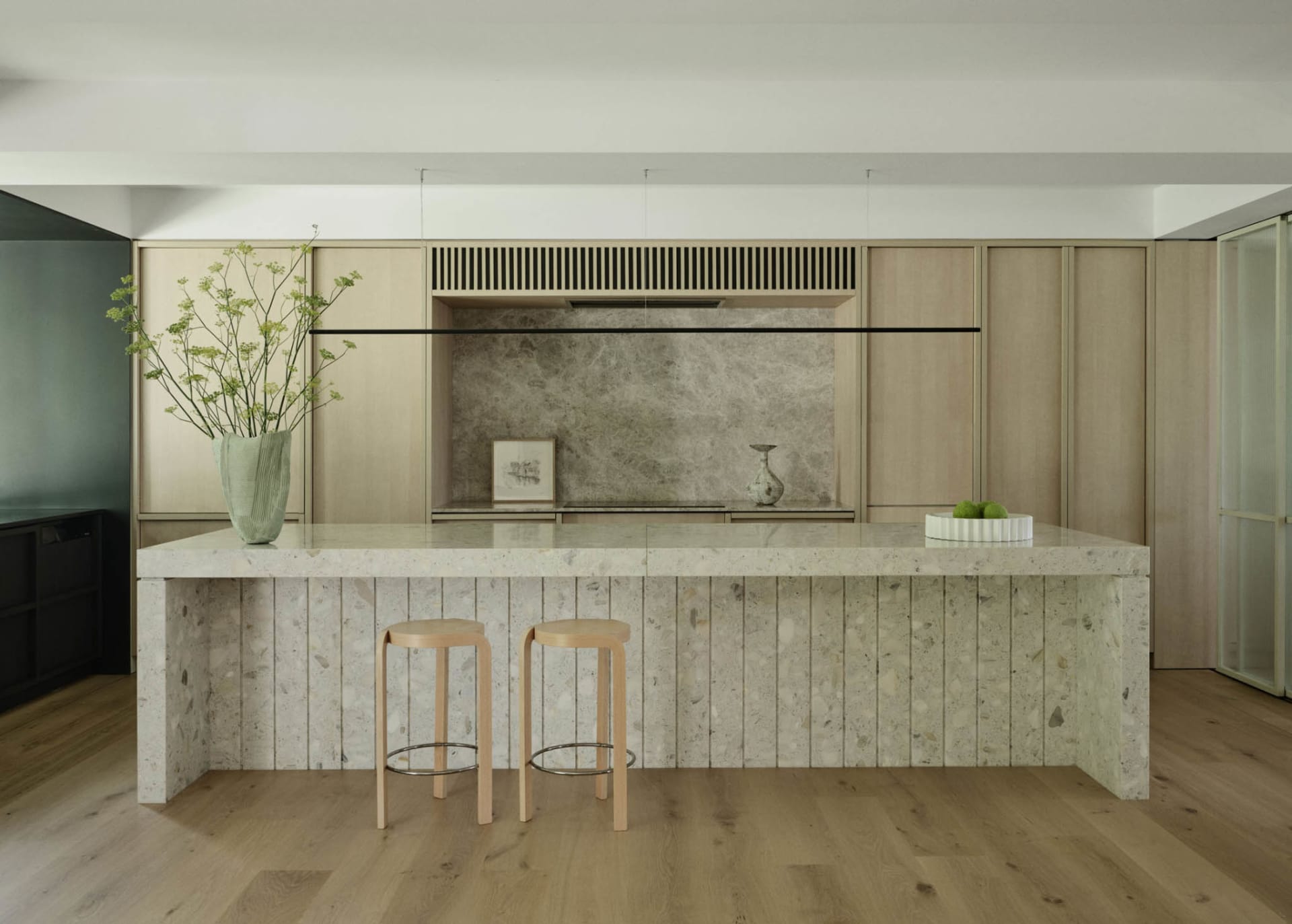 Modern kitchen with marble countertops, wood accents, and terrazzo finishes.