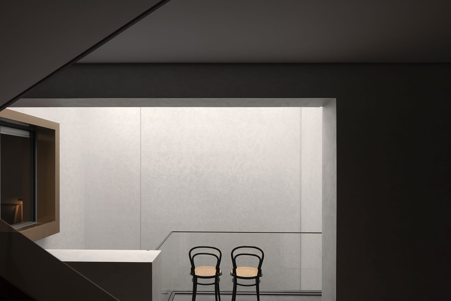 Two minimalist chairs in a modern, minimalist concrete interior space.