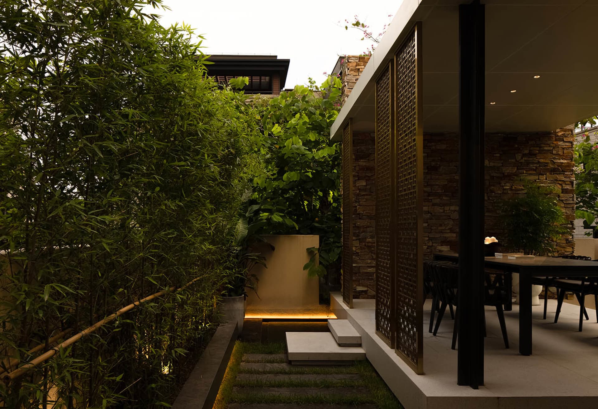 A minimalist patio area with stone walls and a modern table setting.