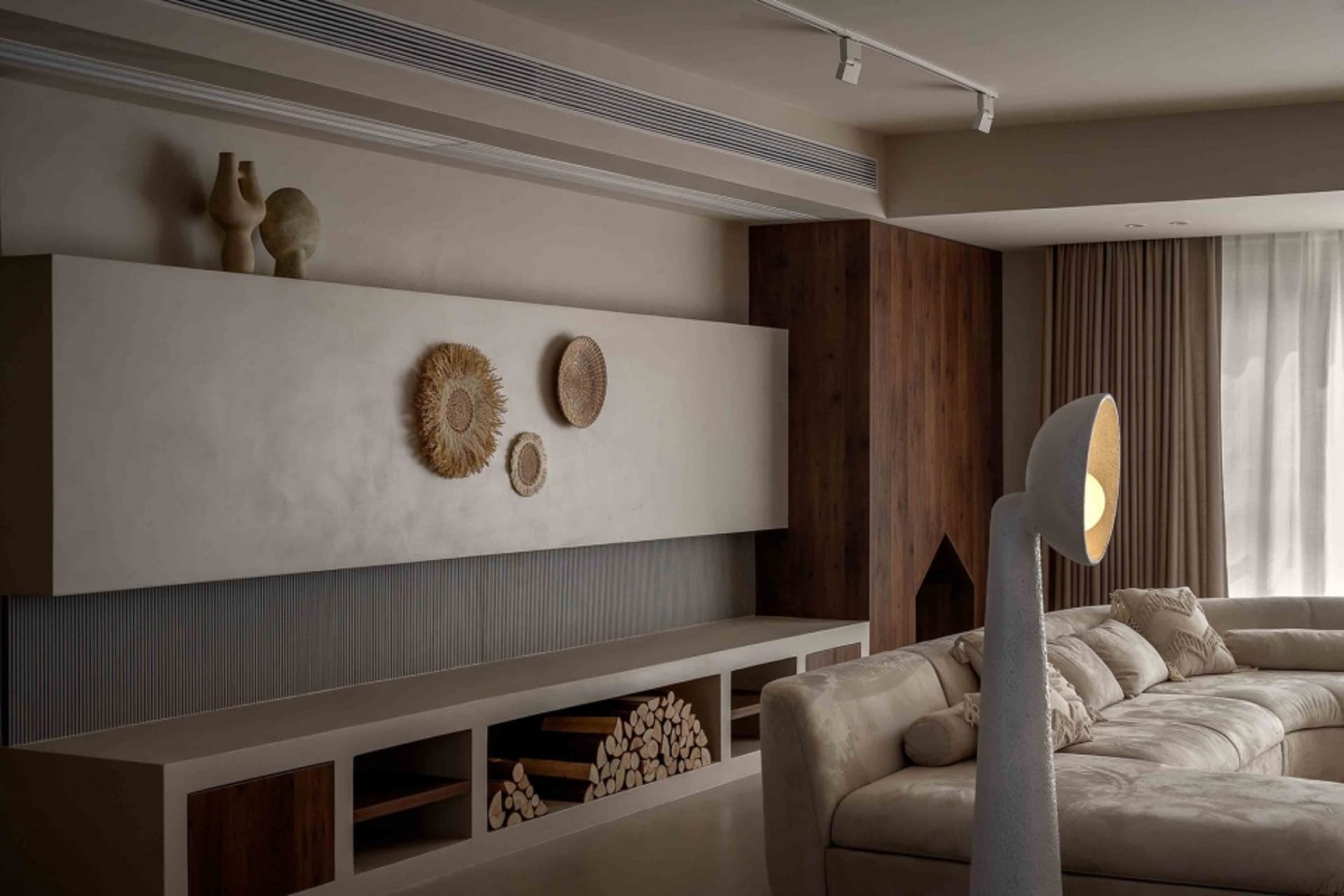Modern living room with concrete walls, wooden furniture, and textured decorative elements.