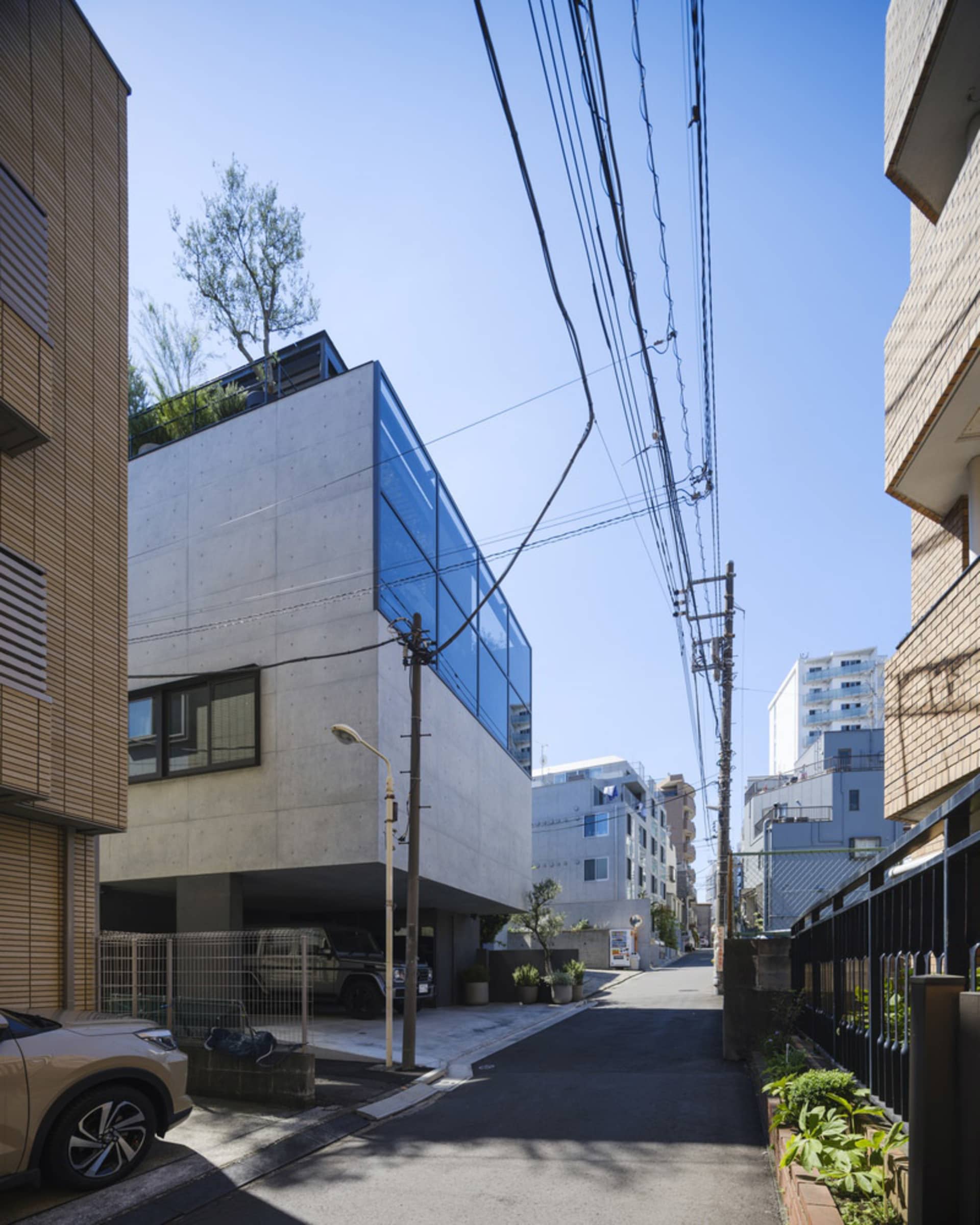 A modern residential house with a concrete exterior and blue glass panels.