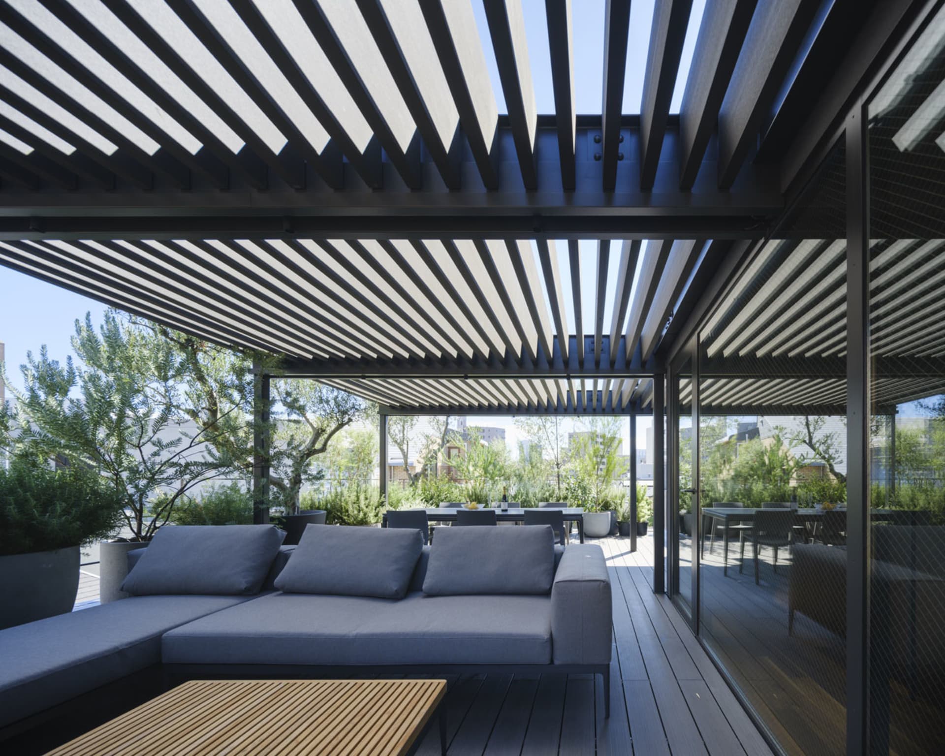 A modern sustainable rooftop deck with a wooden roof, metal shading, and greenery.