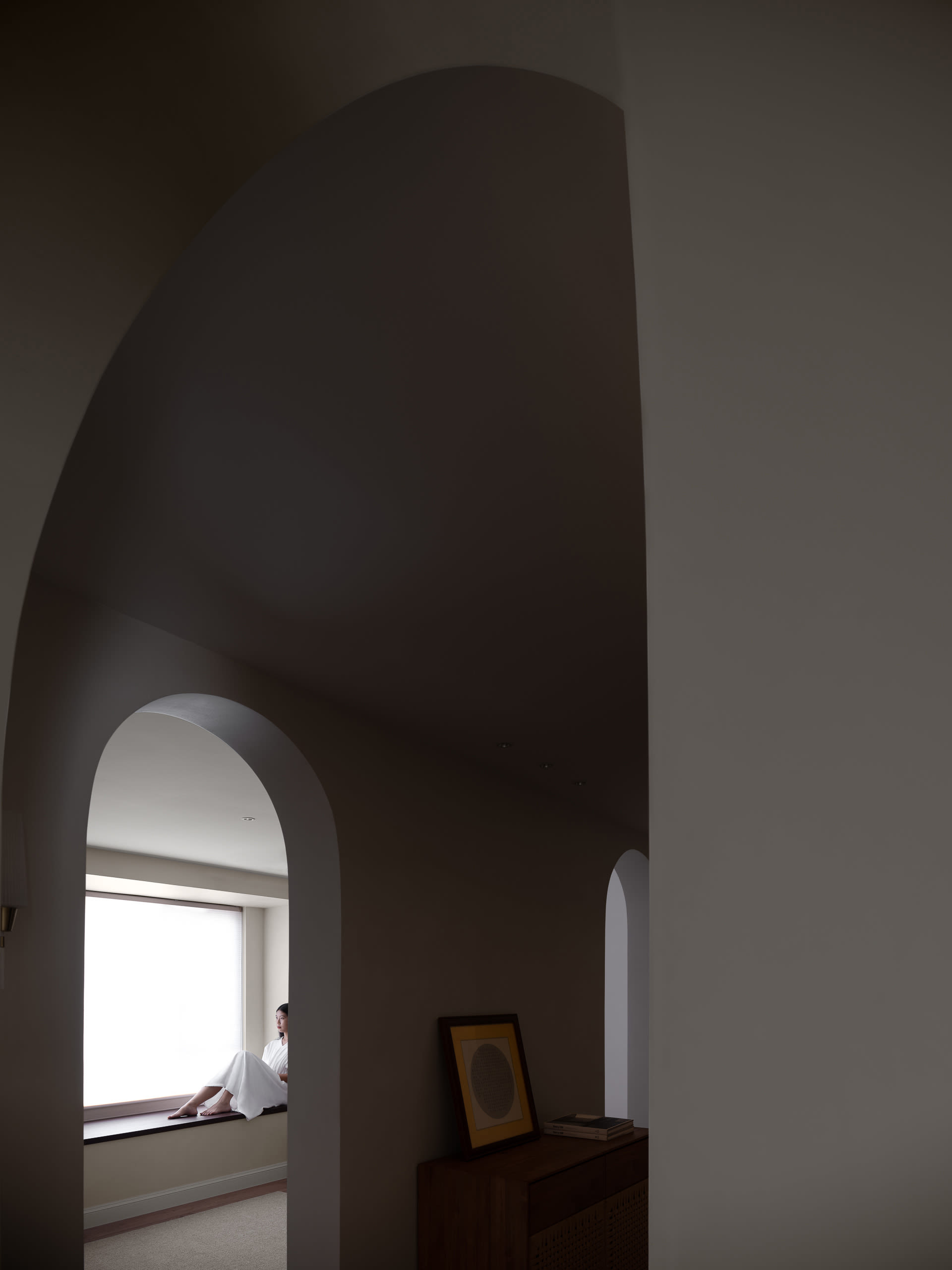 A minimalist interior space with concrete walls and a large window.