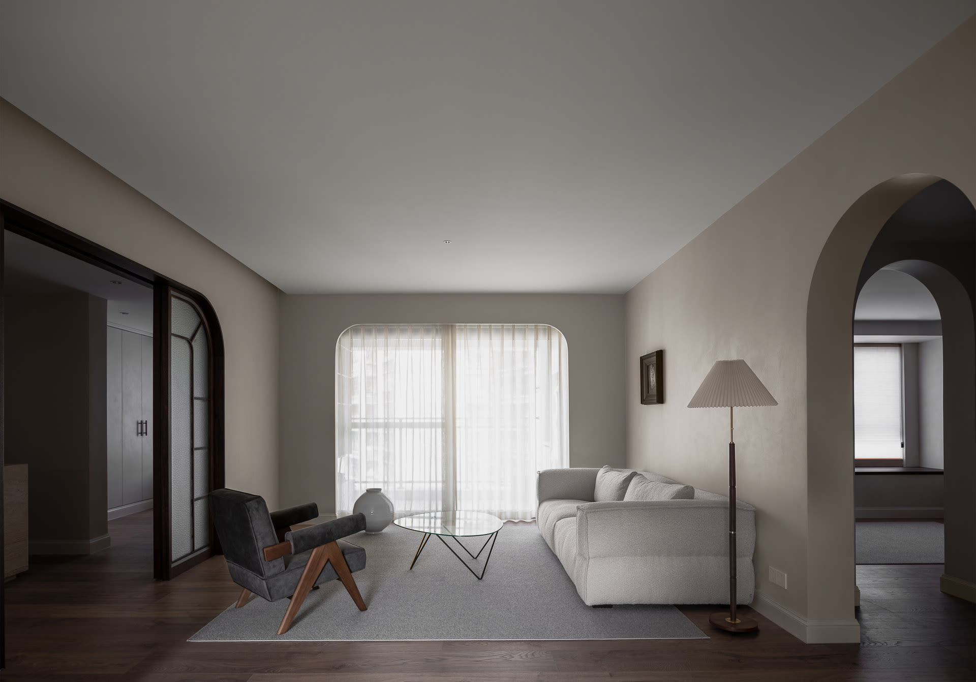 A minimalist living room with neutral-toned decor and a glass coffee table.