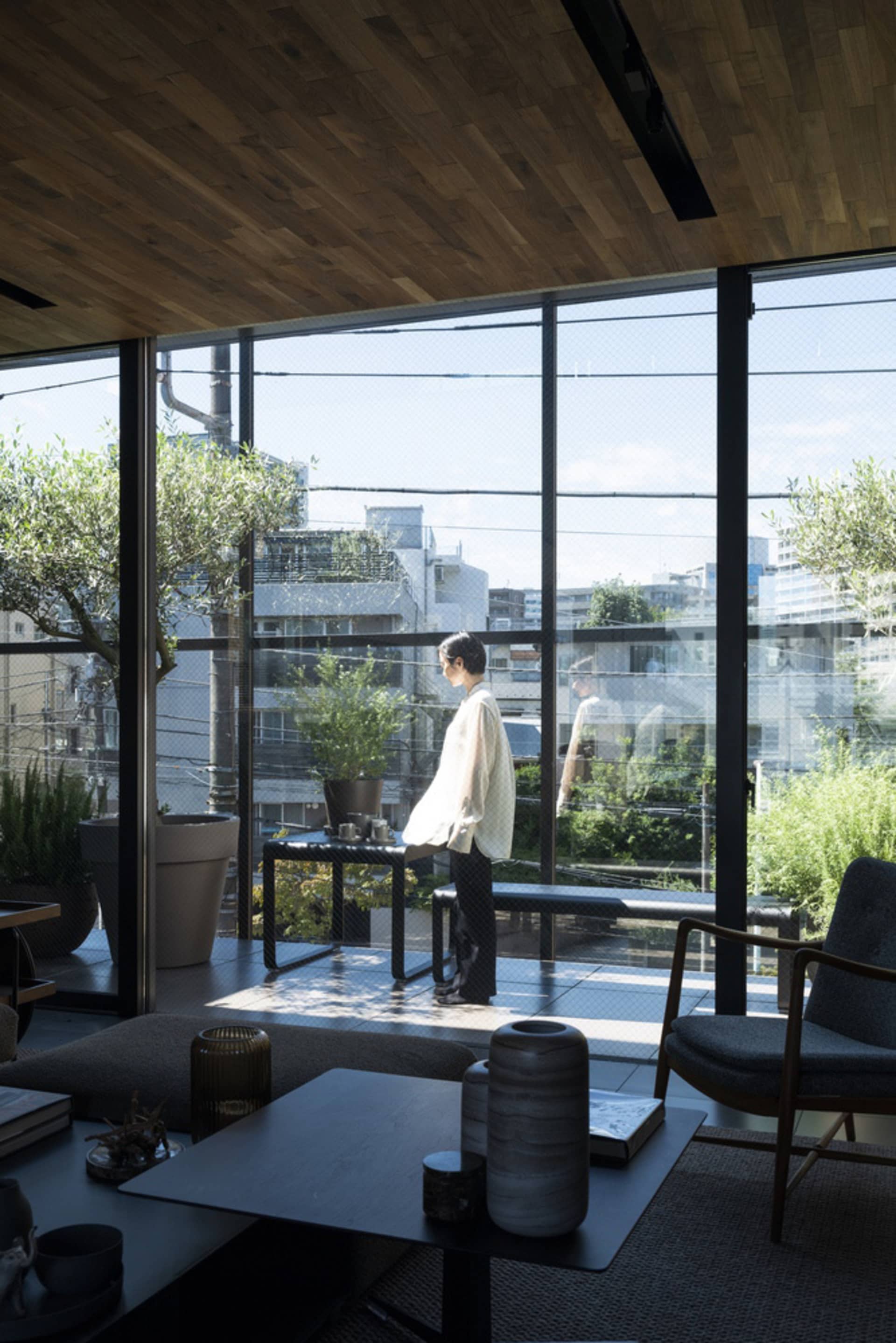 A modern living room with glass windows and minimal furniture.
