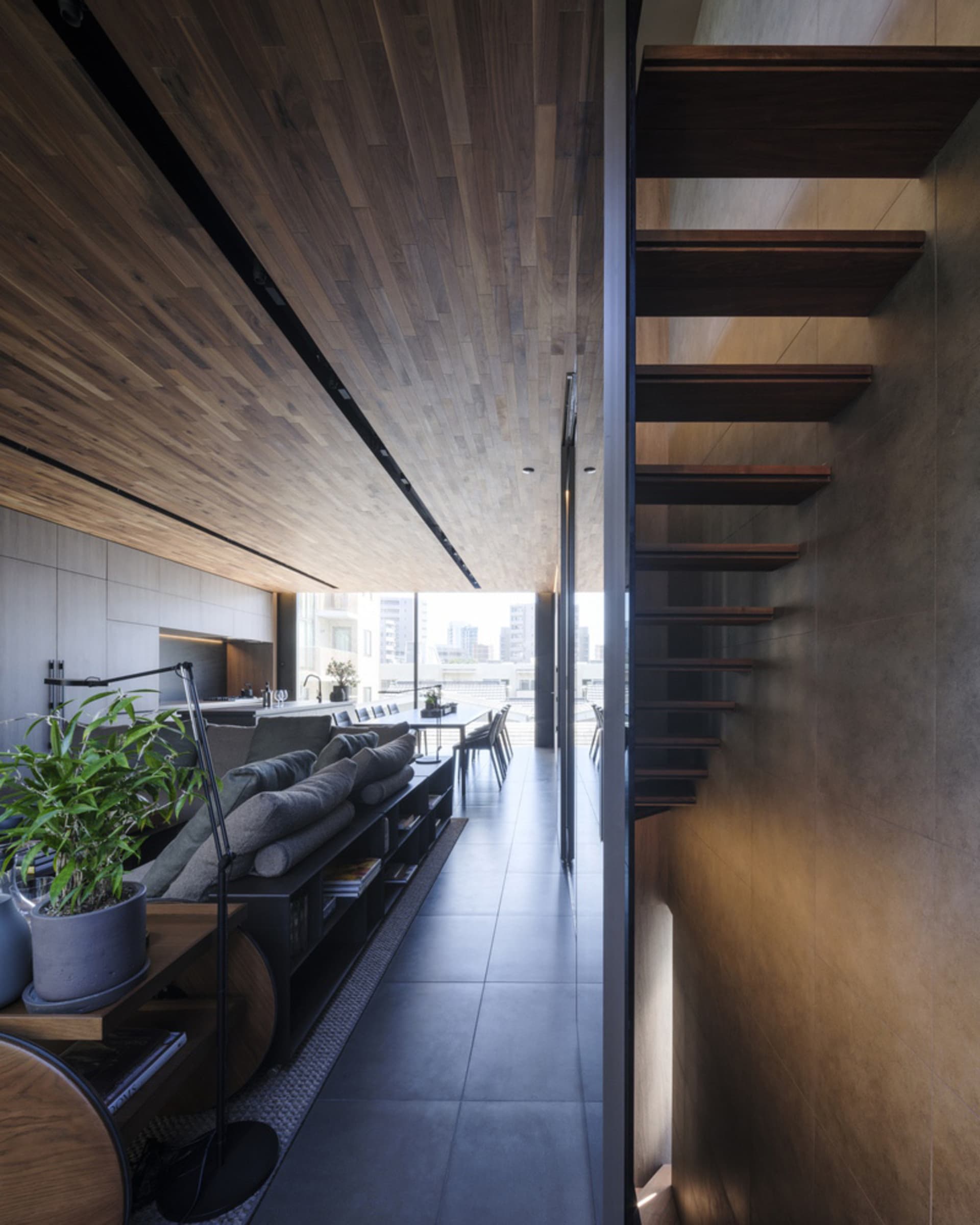 Modern, minimalist living room with wooden flooring and concrete walls.