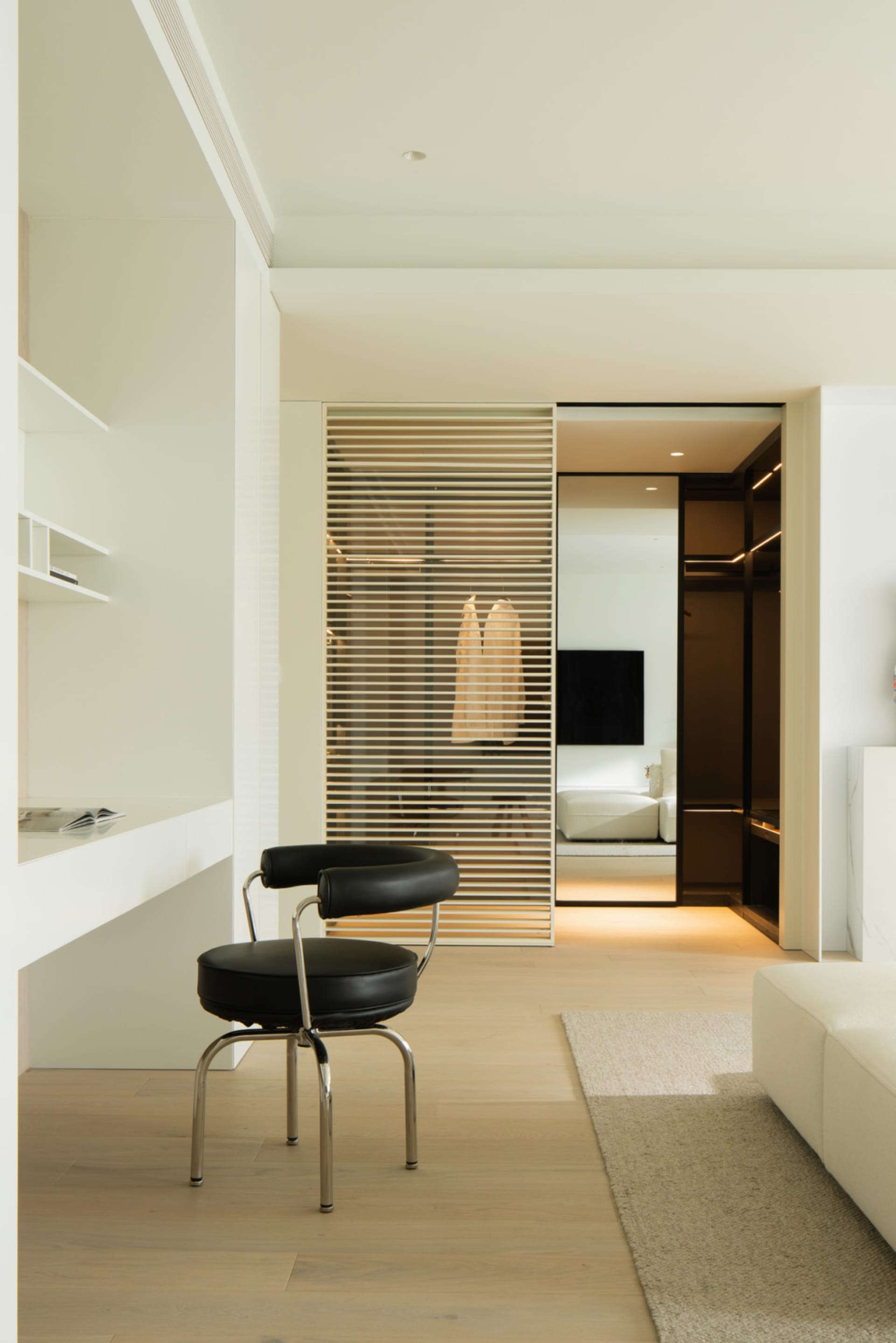 Modern minimalist office space with white furniture and open closet.
