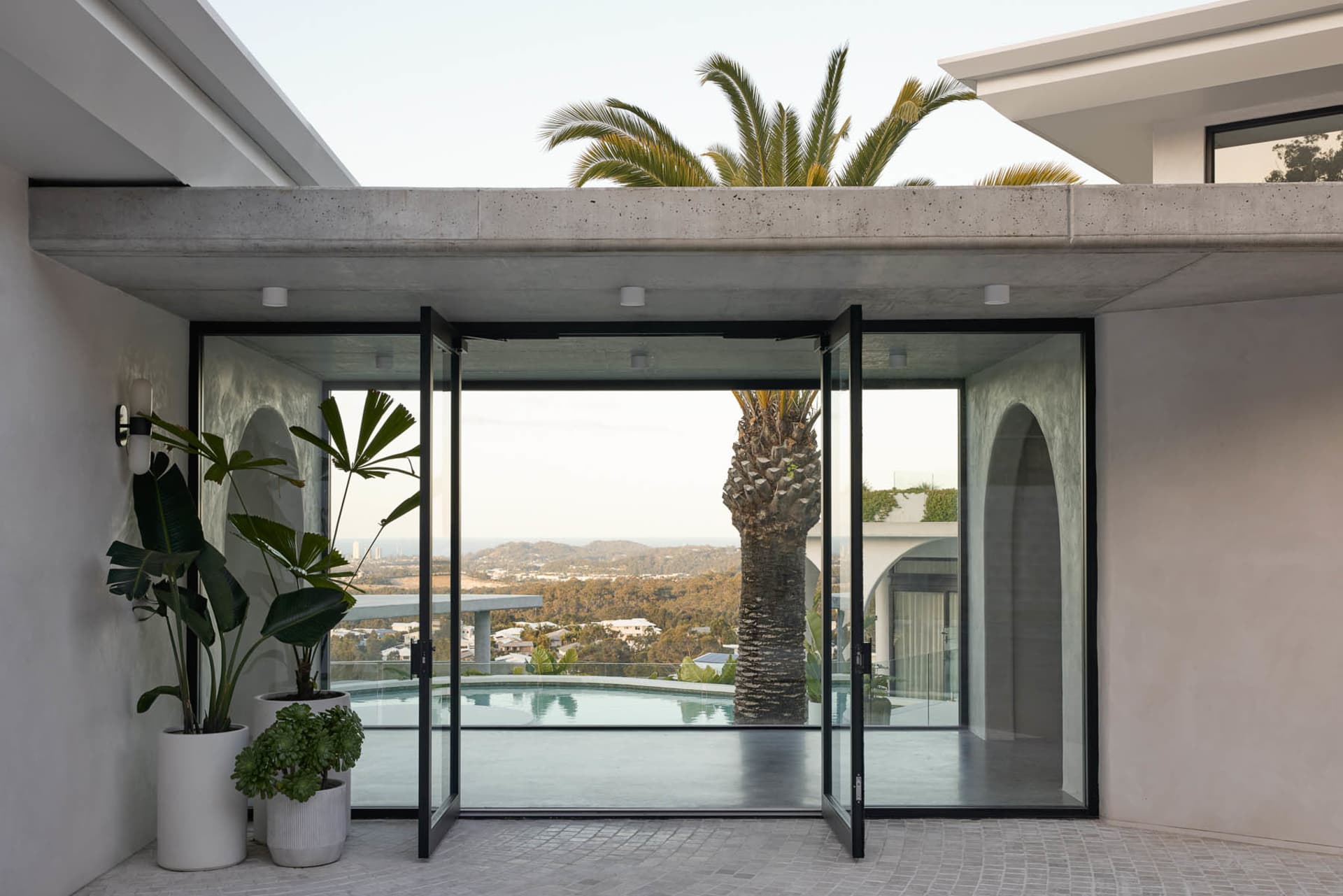 A modern residential exterior with concrete and glass elements featuring a pool and scenic view.