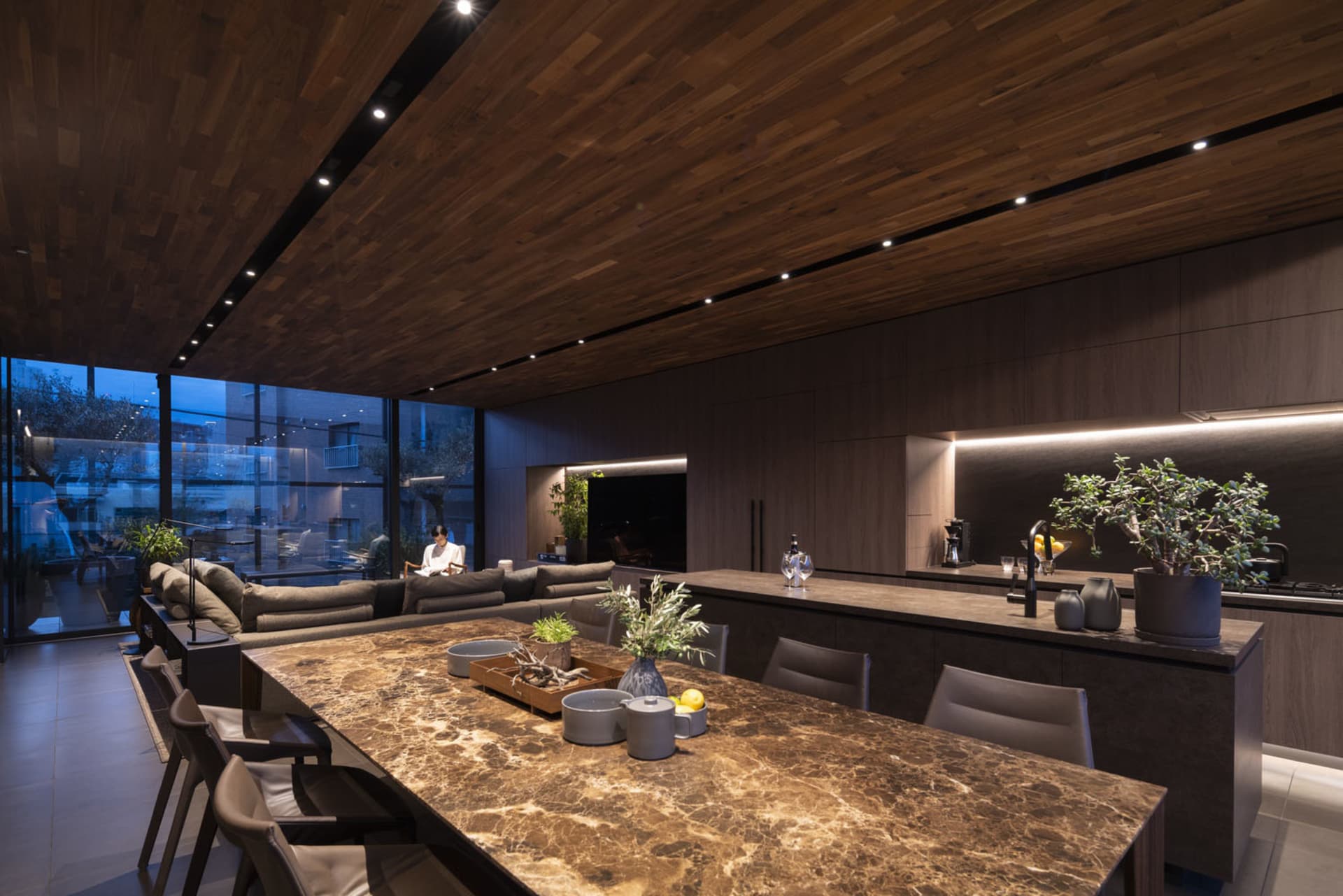 Modern residential kitchen with marble countertops, dark wood ceiling, and built-in lighting.