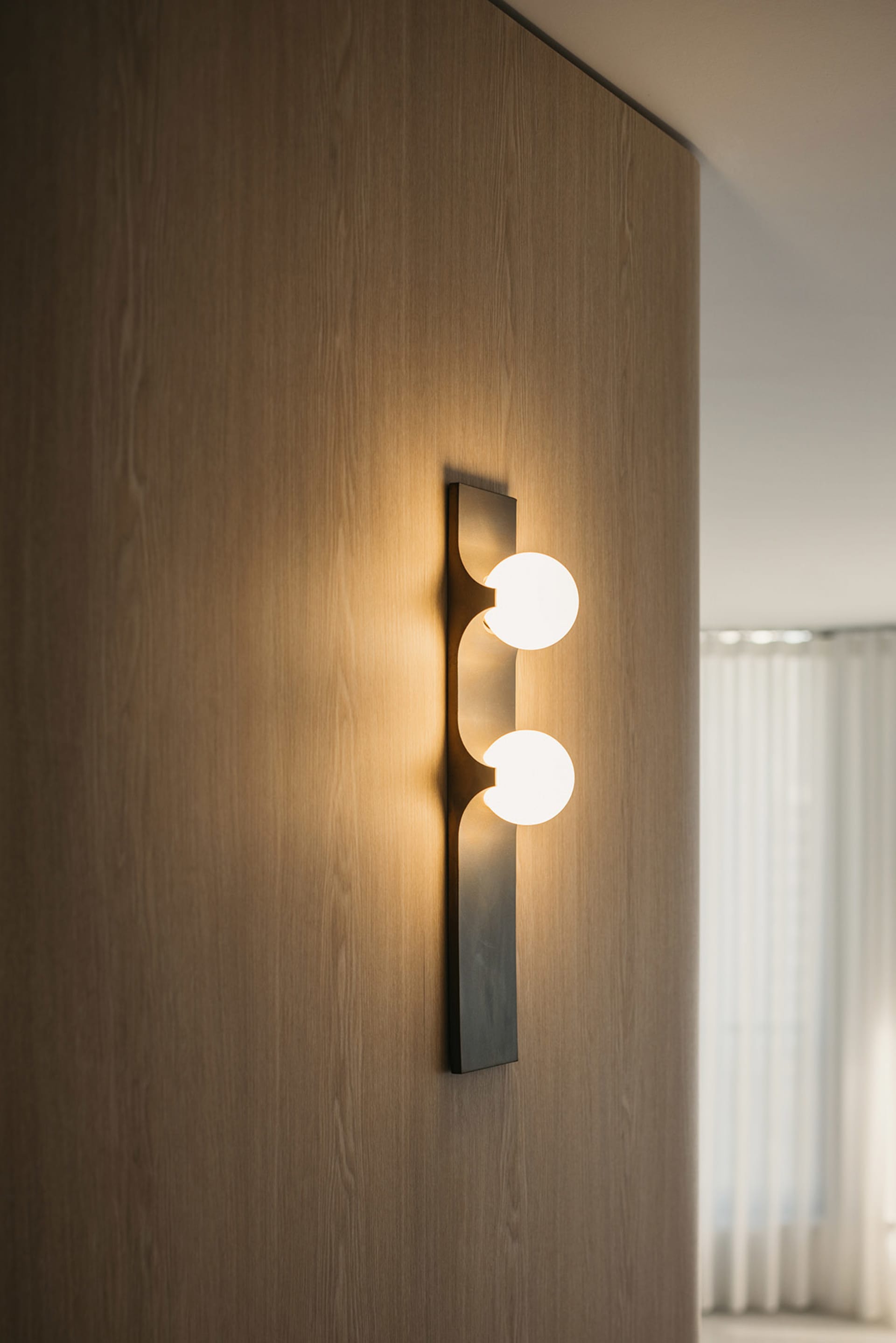 Modern, minimalist design wall lamp with two glass bulbs on a wooden wall.