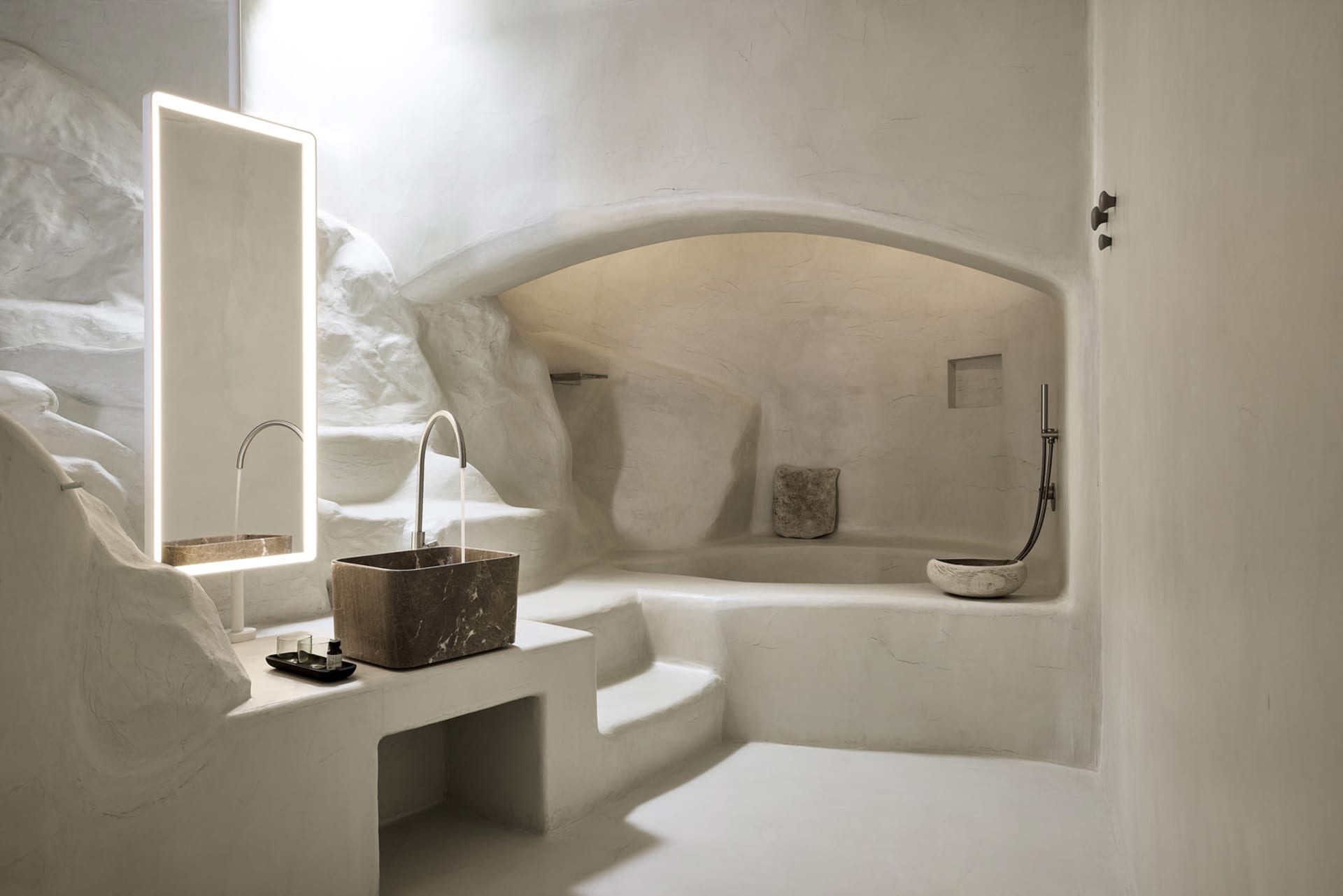 Modern bathroom interior designed with stone elements, featuring a sink, mirror, and textured walls.