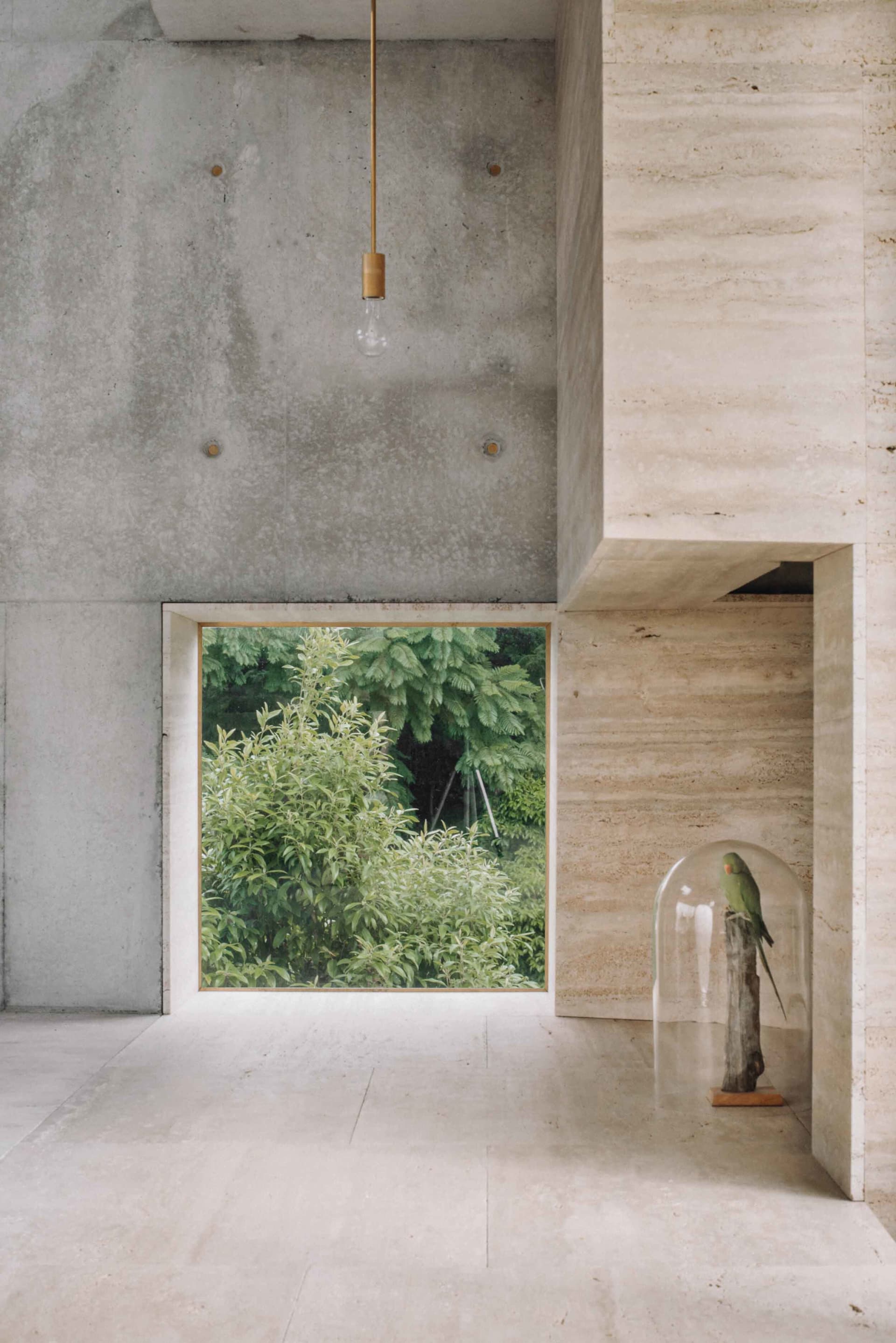 Minimalist concrete interior with a pendant light and a glass dome featuring a bird.