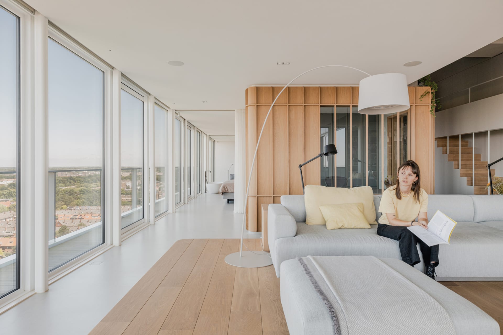 Modern living room featuring a comfortable sofa and wooden accents, set against a large window with a scenic view.