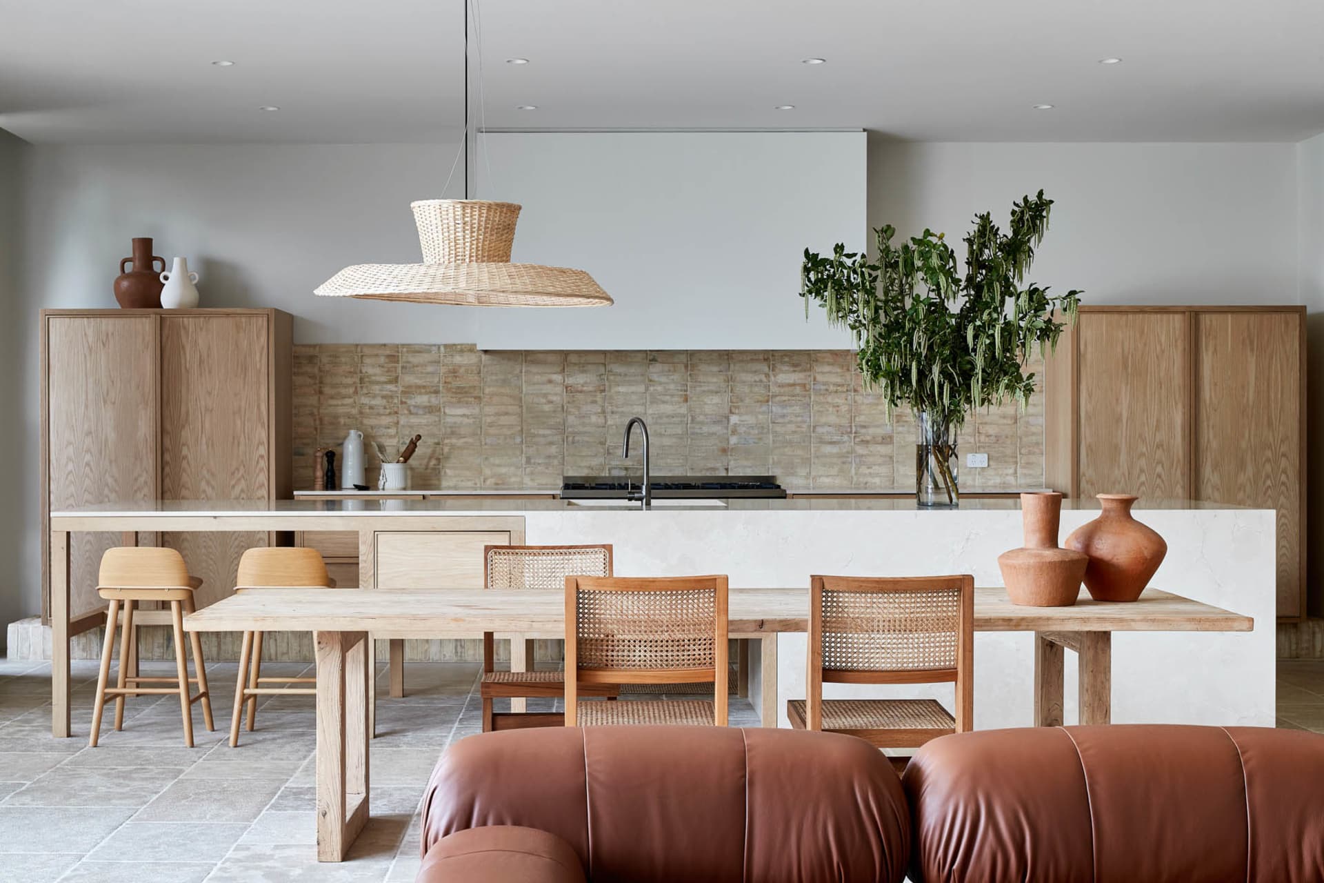 Modern residential kitchen featuring wooden tables and chairs with a marble countertop.