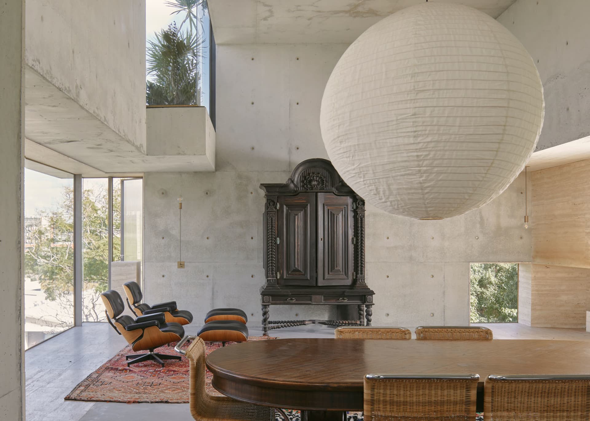 A modern living room with concrete walls, a large spherical pendant light, and minimalist furniture.
