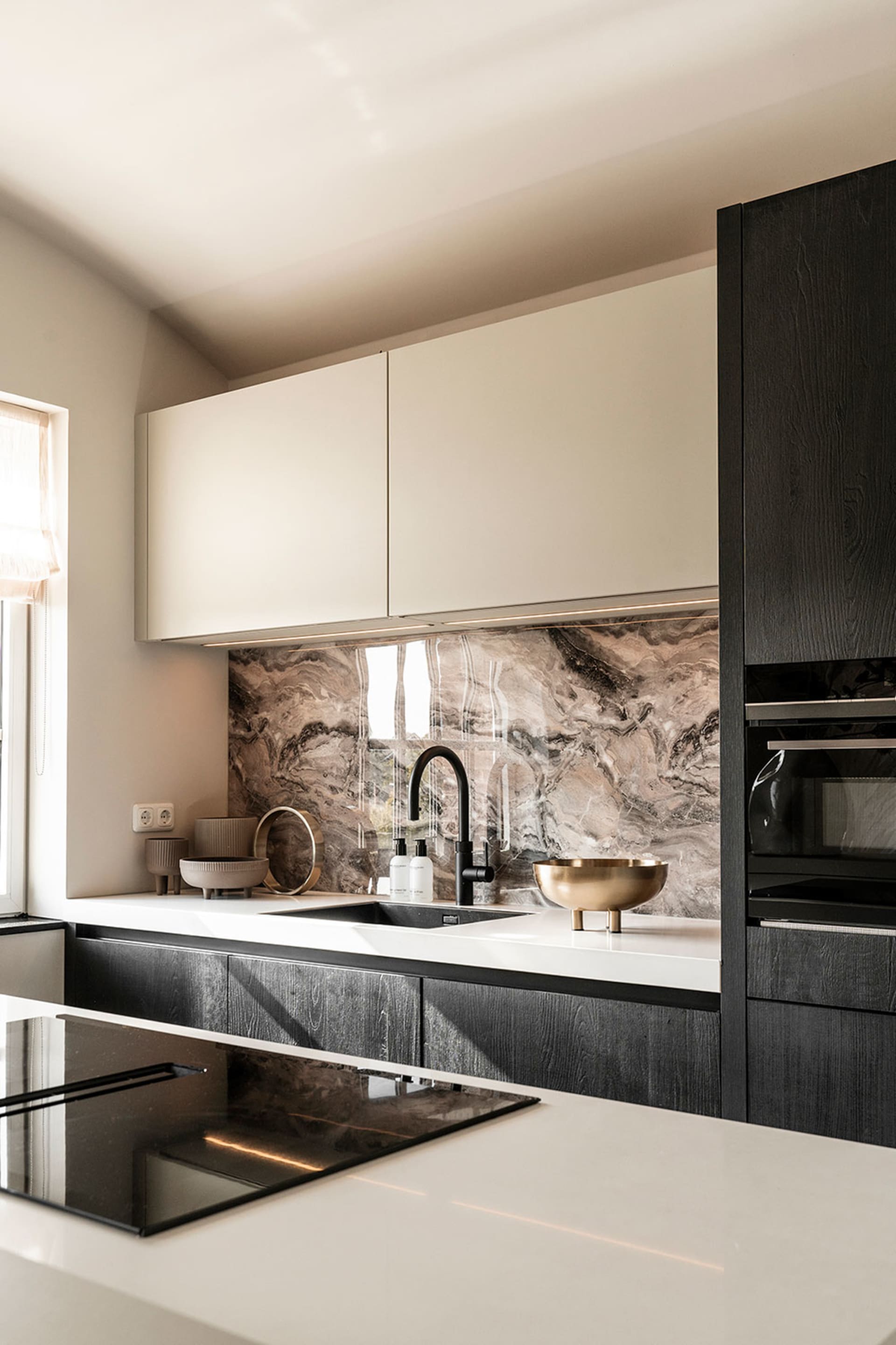 Modern residential kitchen featuring marble countertops and backsplash.