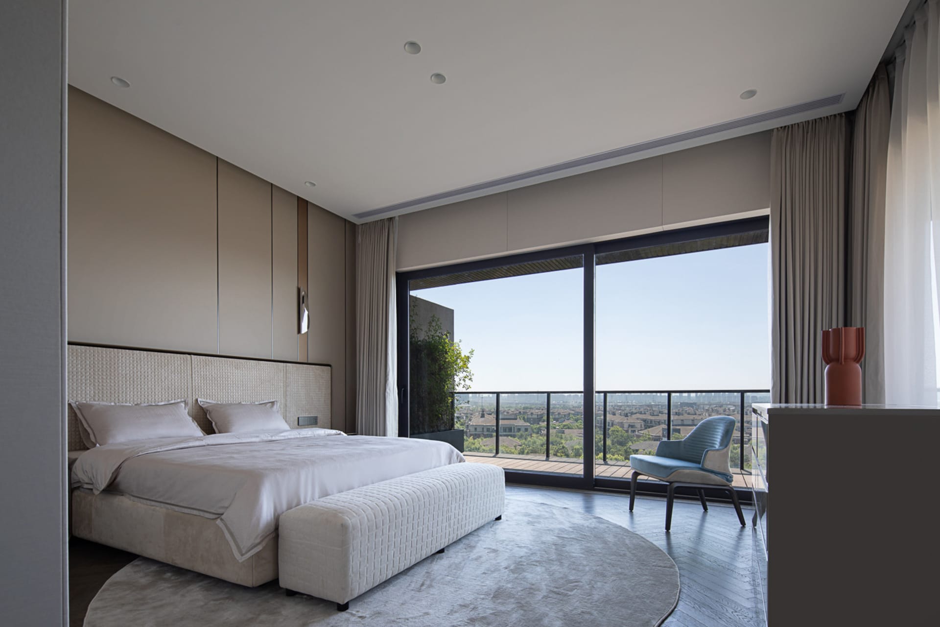 A modern bedroom with a large bed, white bedding, and neutral-colored furniture in a contemporary living space.
