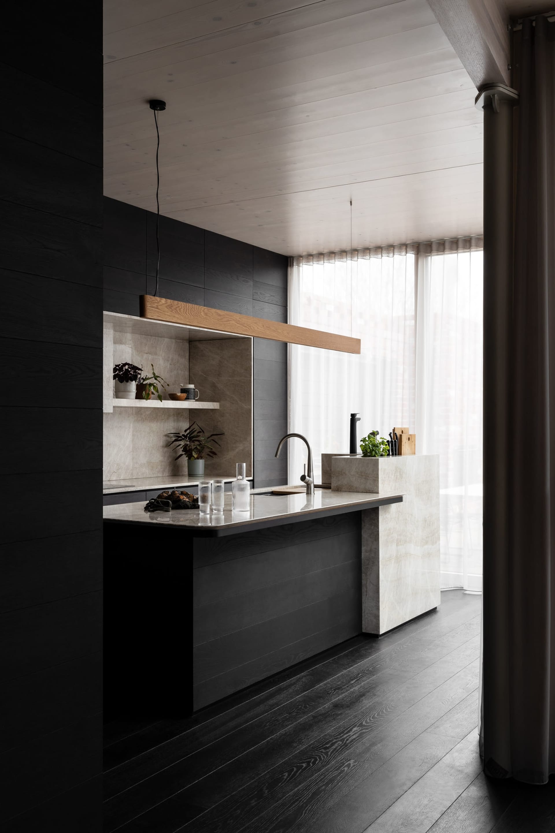 Modern kitchen with marble countertops and black wooden floors.