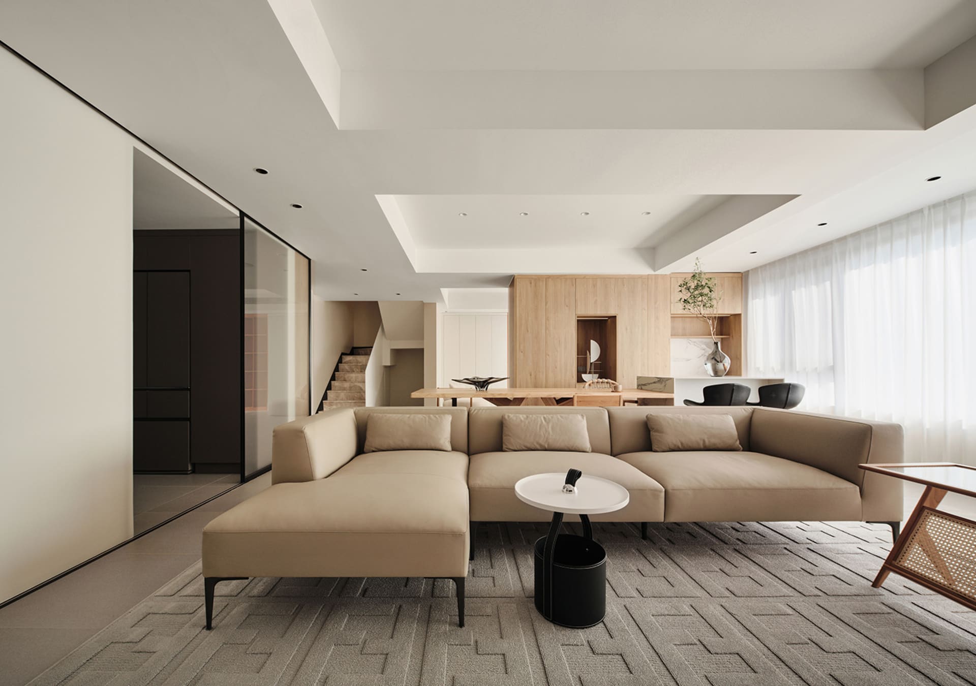 Modern minimalist living room featuring a beige sectional sofa, white coffee table, and light wood elements.