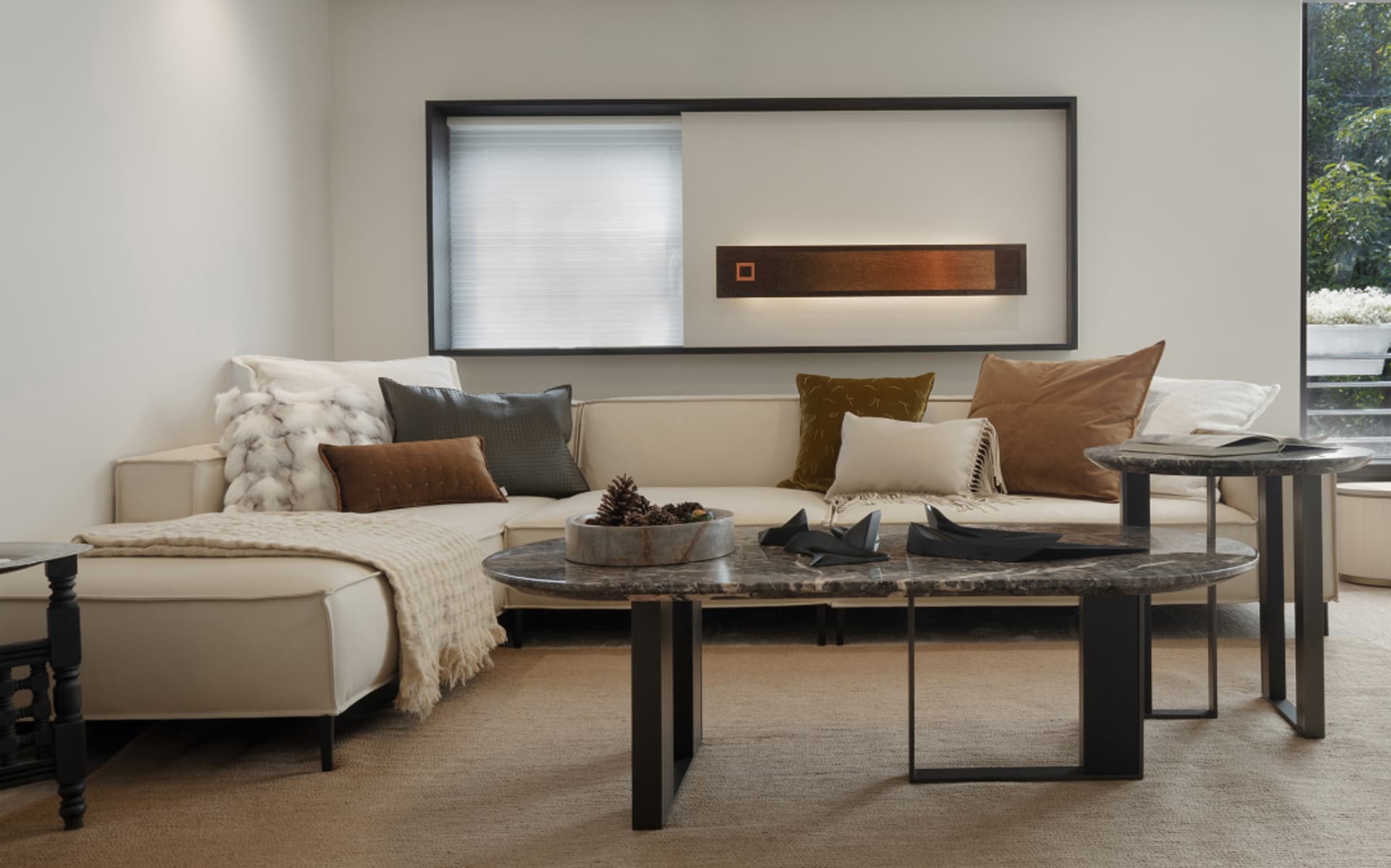 A modern minimalist living room featuring a white sectional couch adorned with a variety of textured throw pillows, a marble
